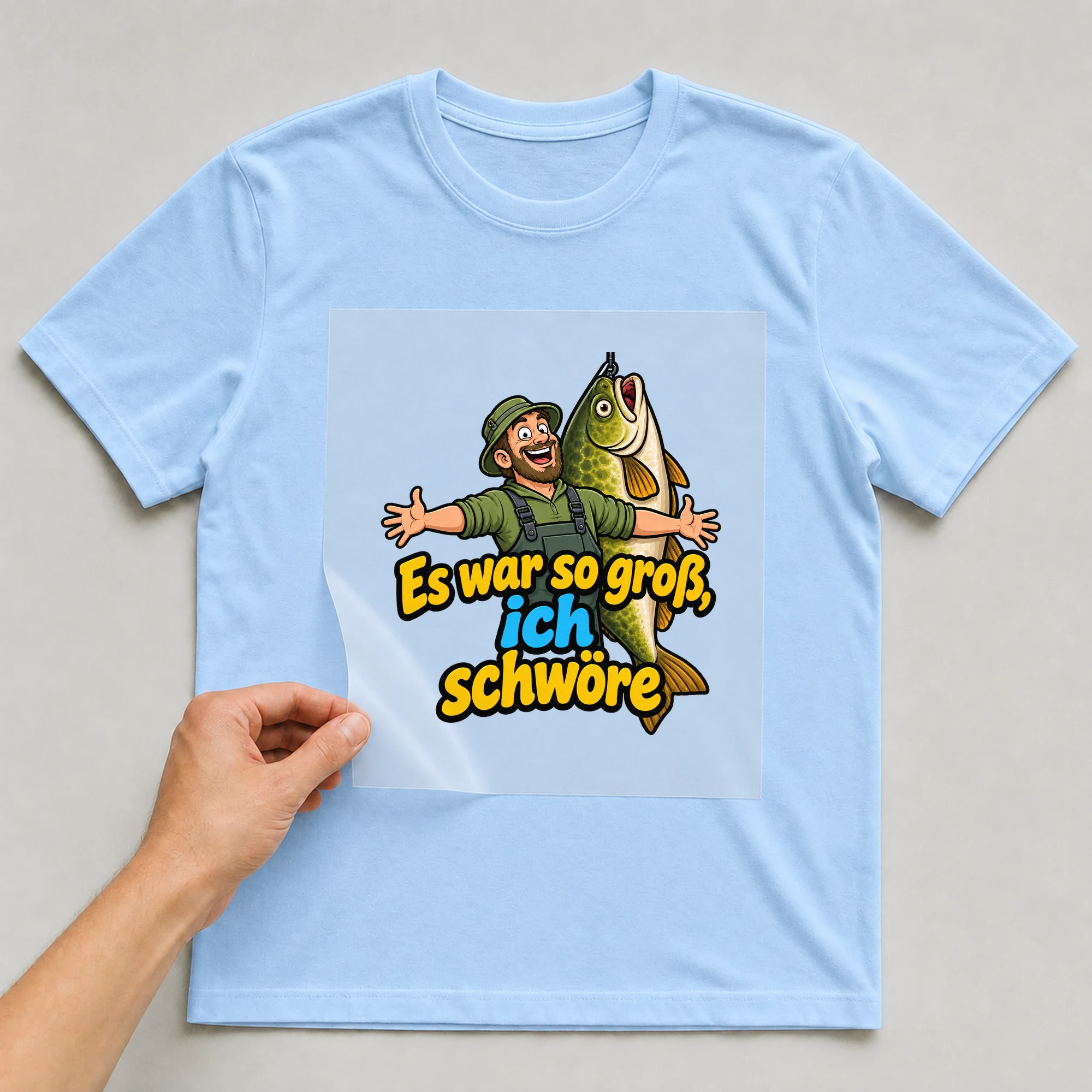 Bügelbild „Es war so groß, ich schwöre“ auf babyblauem T-Shirt, Folie wird aufgelegt