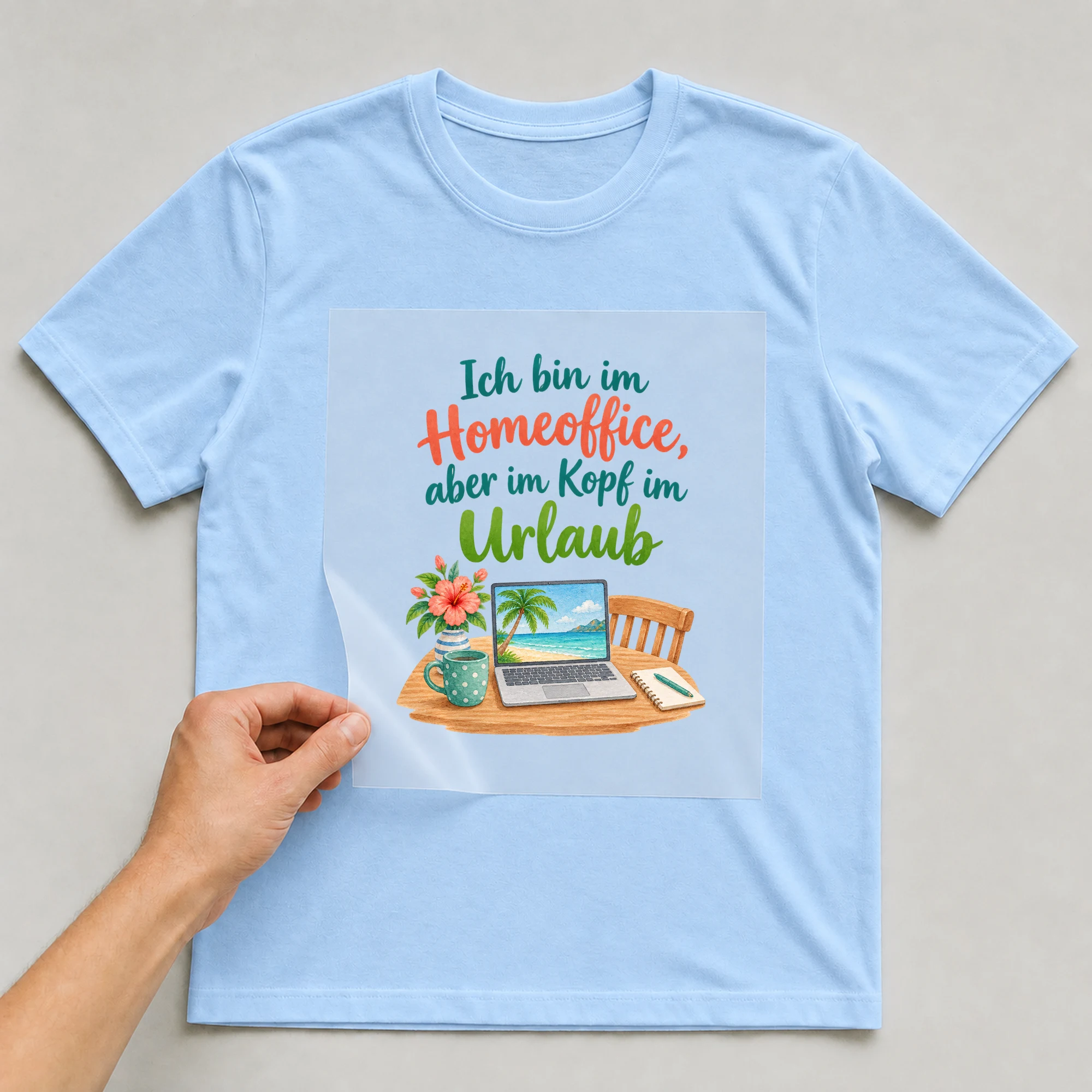 Bügelbild „Ich bin im Homeoffice, aber im Kopf im Urlaub“ auf babyblauem T-Shirt, Folie wird aufgelegt