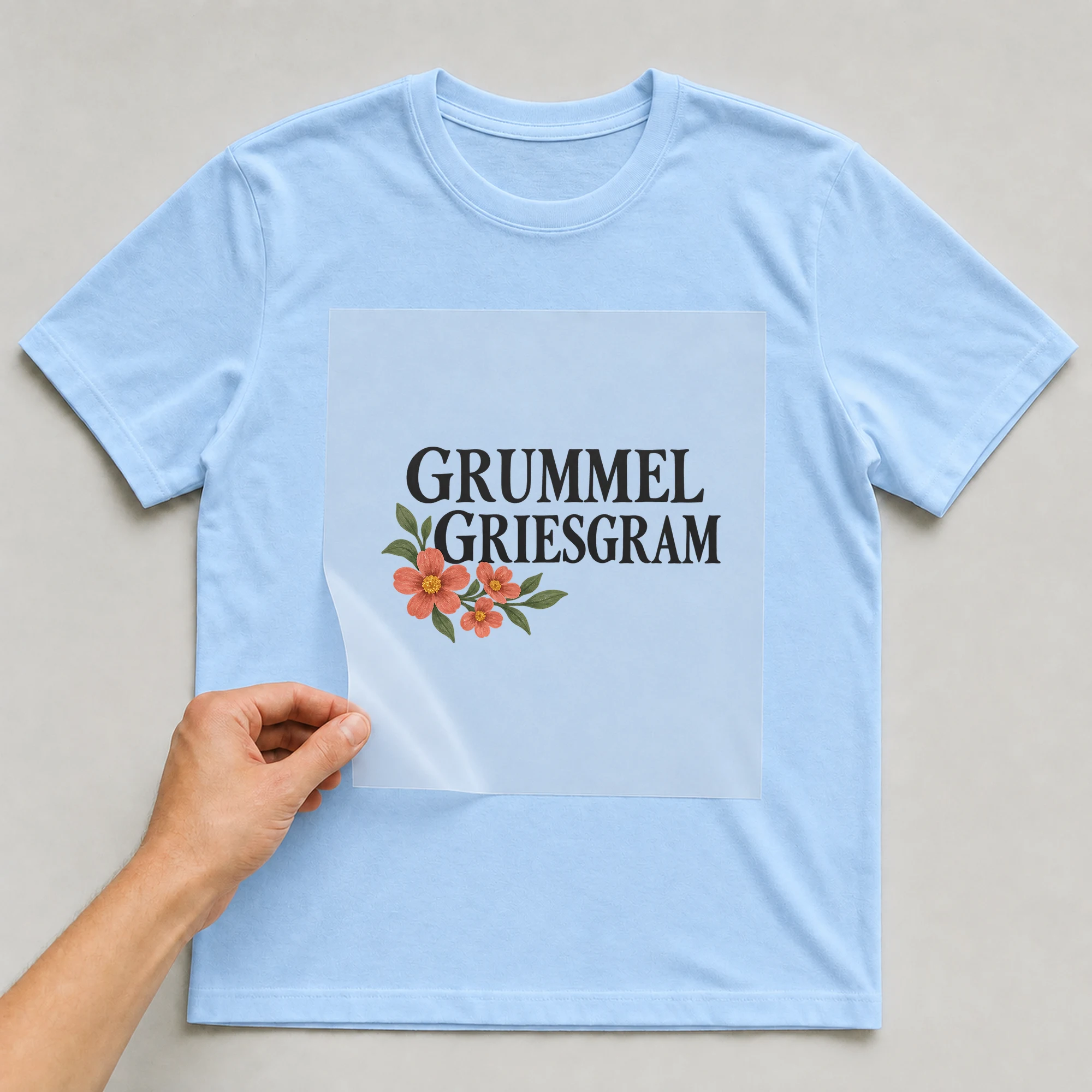 Bügelbild „Grummel Griesgram“ auf babyblauem T-Shirt, Folie wird aufgelegt
