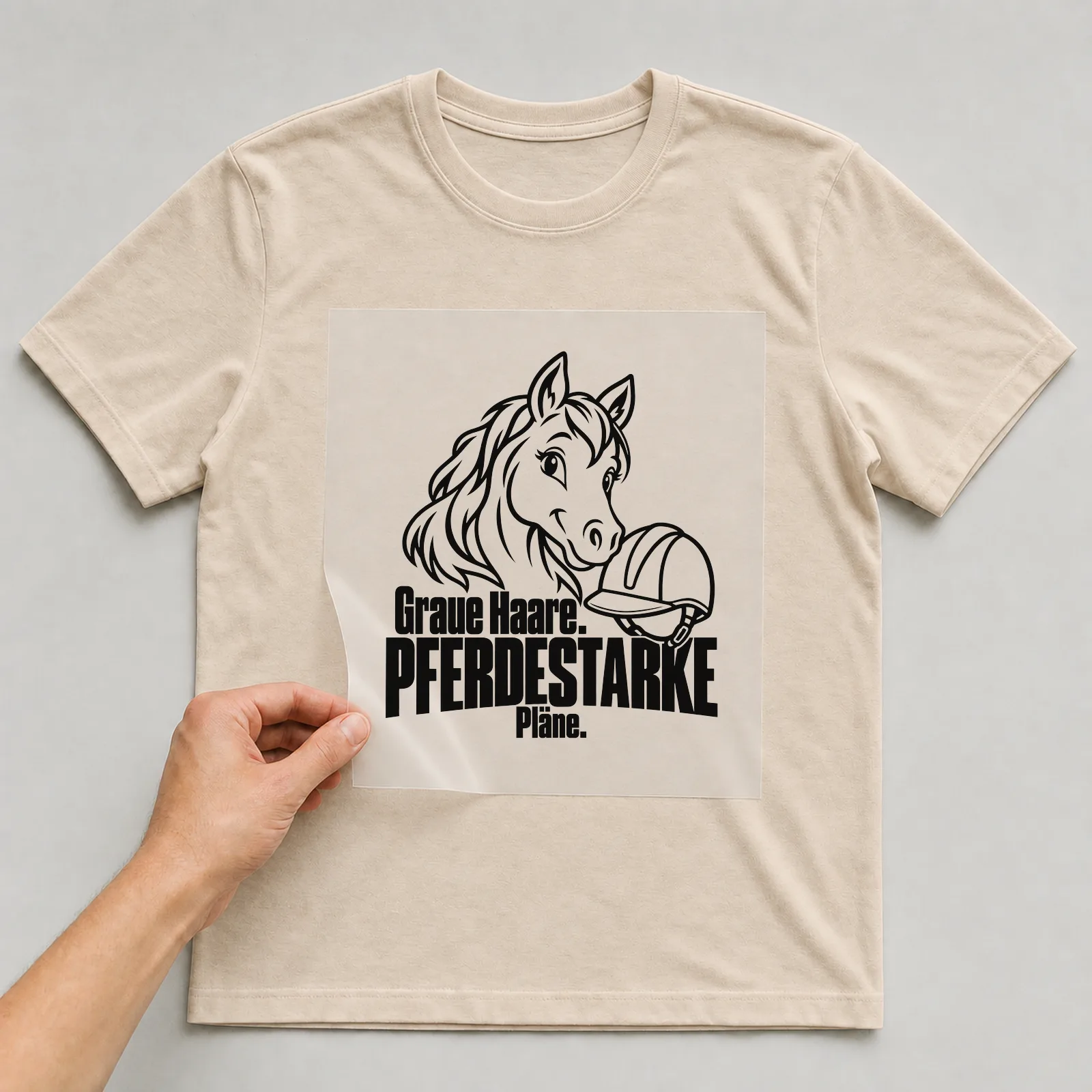 Bügelbild „Graue Haare. Pferdestarke Pläne.“ auf beigem T-Shirt, Folie wird aufgelegt
