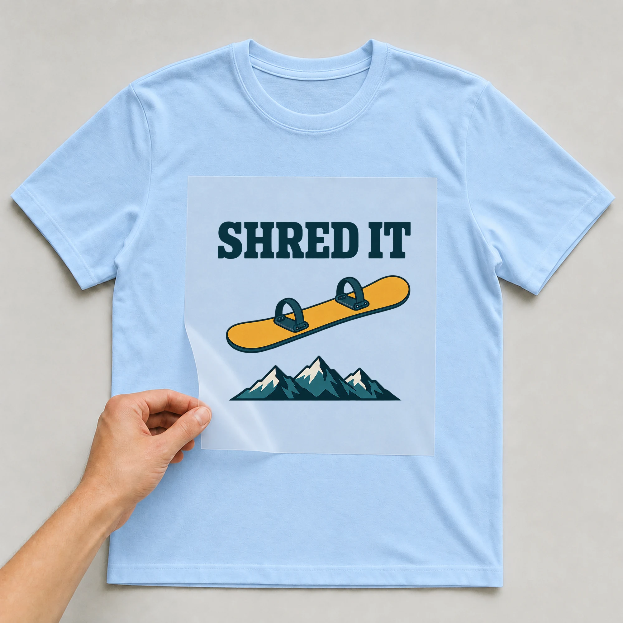 Bügelbild „SHRED IT“ auf babyblauem T-Shirt, Folie wird aufgelegt