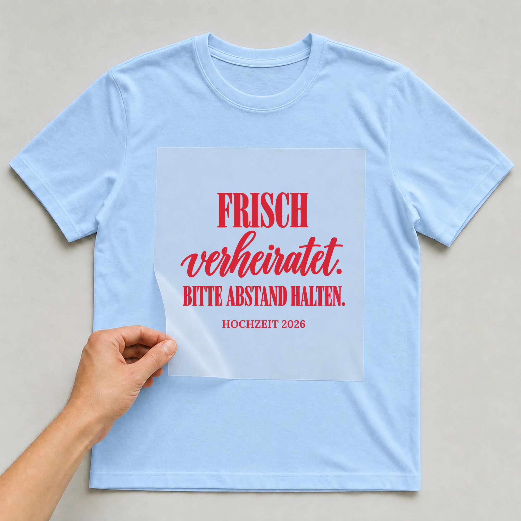 Bügelbild Frisch verheiratet. Bitte Abstand halten mit Jahr auf hellblauem T-Shirt, Folie wird aufgelegt