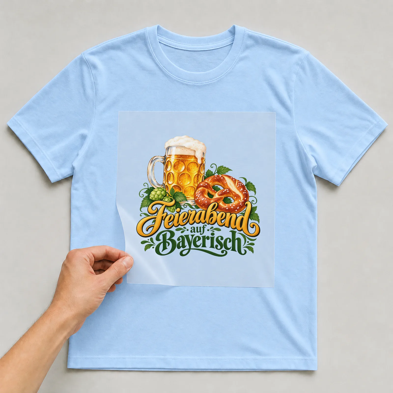 Bügelbild „Feierabend auf Bayerisch“ auf hellblauem T-Shirt, Folie wird aufgelegt