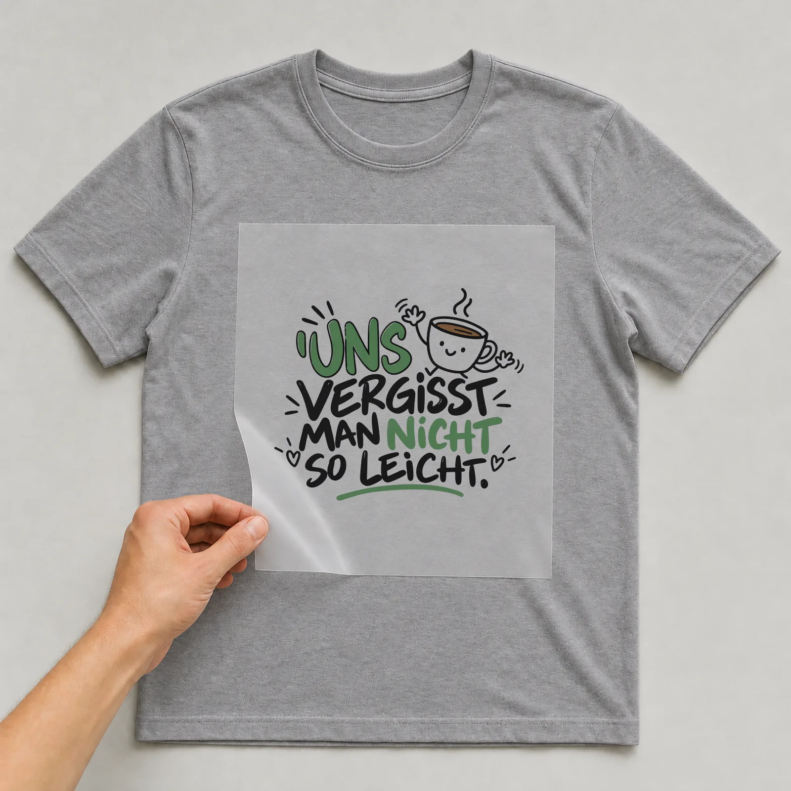 Bügelbild „Uns vergisst man nicht so leicht“ auf grauem T-Shirt, Folie wird aufgelegt