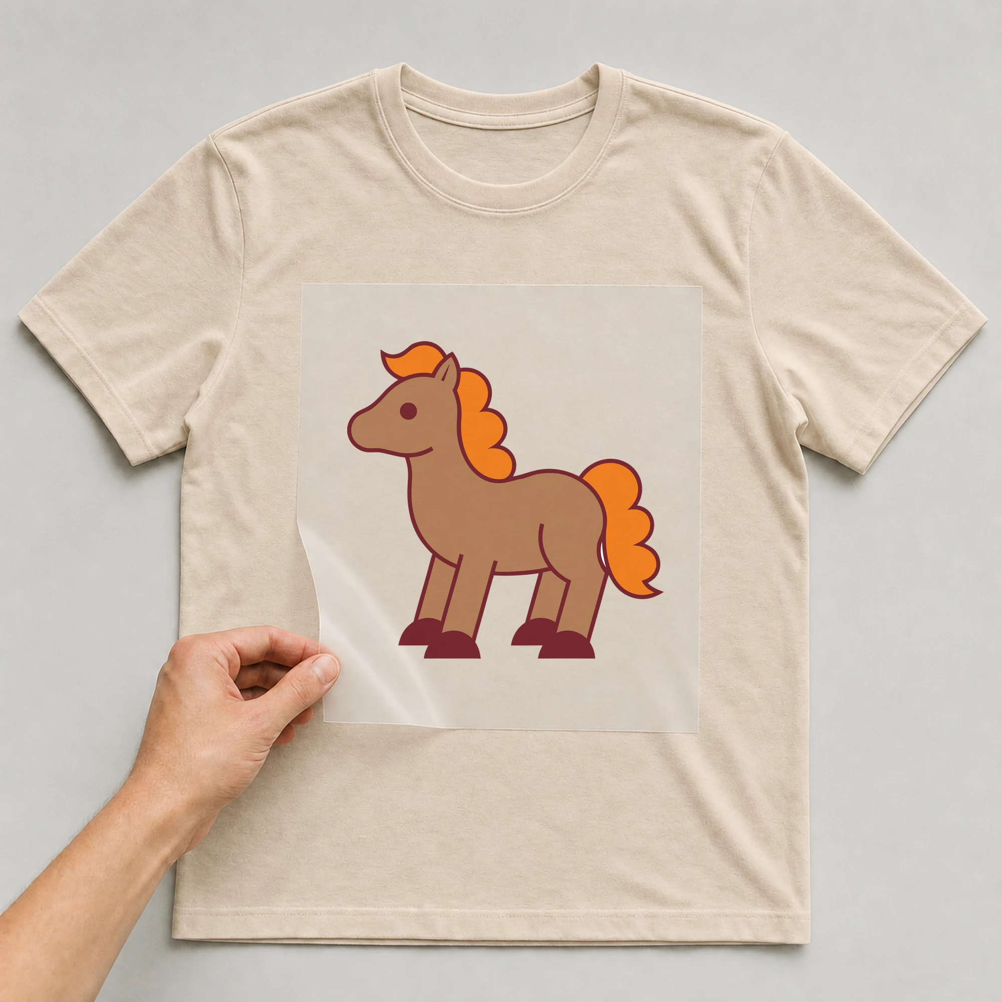 Bügelbild „Pony“ auf beigem T-Shirt, Folie wird aufgelegt