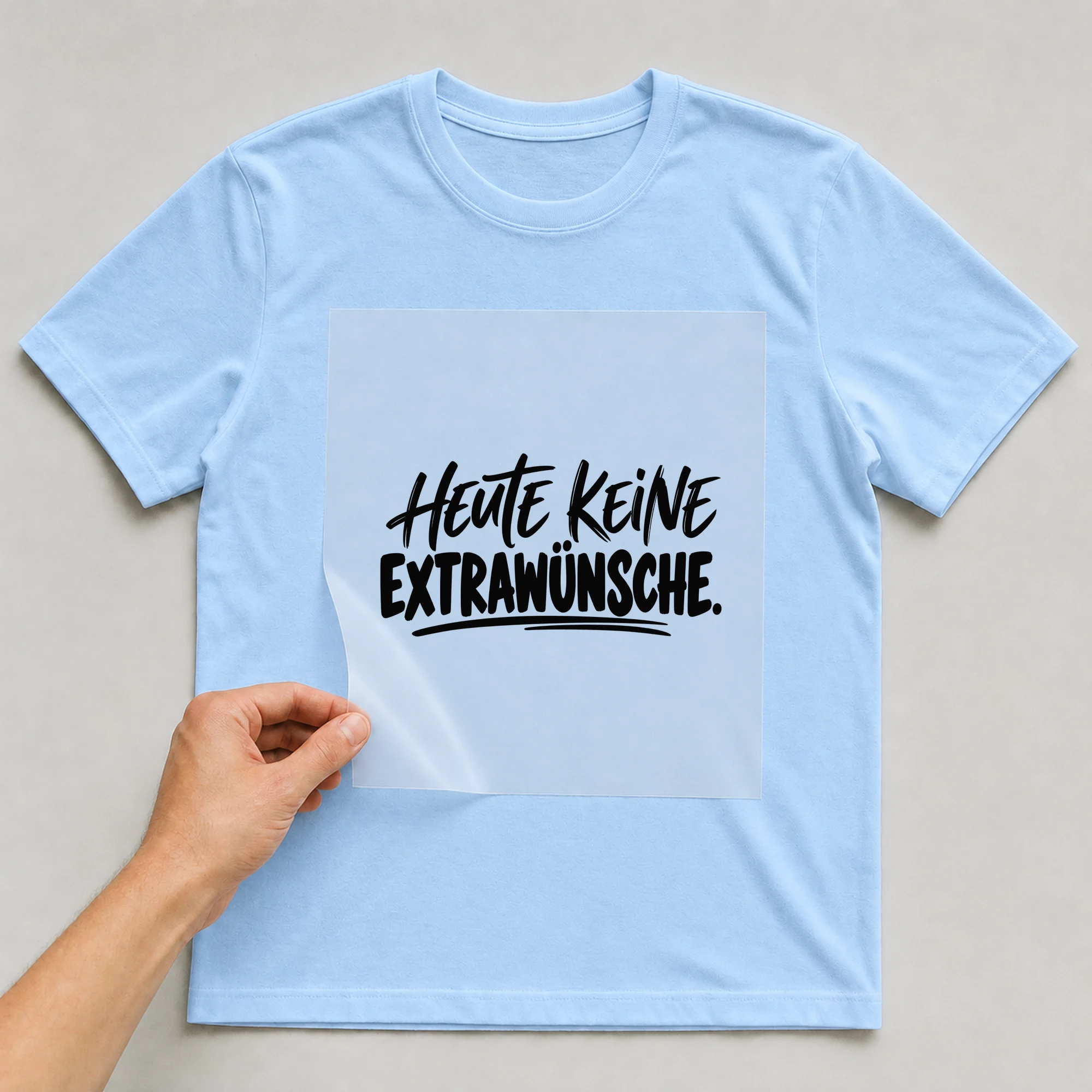 Bügelbild „Heute keine Extrawünsche.“ auf babyblauem T-Shirt, Folie wird aufgelegt