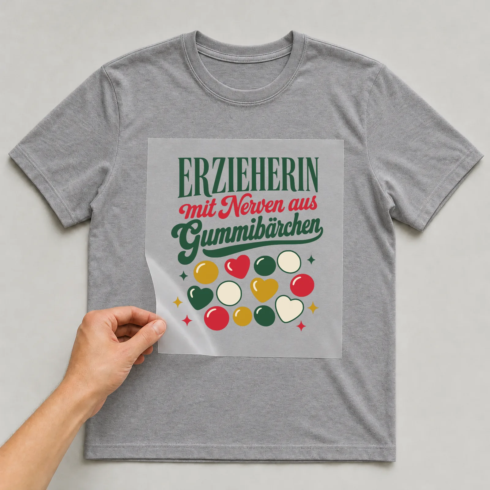 Bügelbild Erzieherin mit Nerven aus Gummibärchen auf grauem T-Shirt, Folie wird aufgelegt