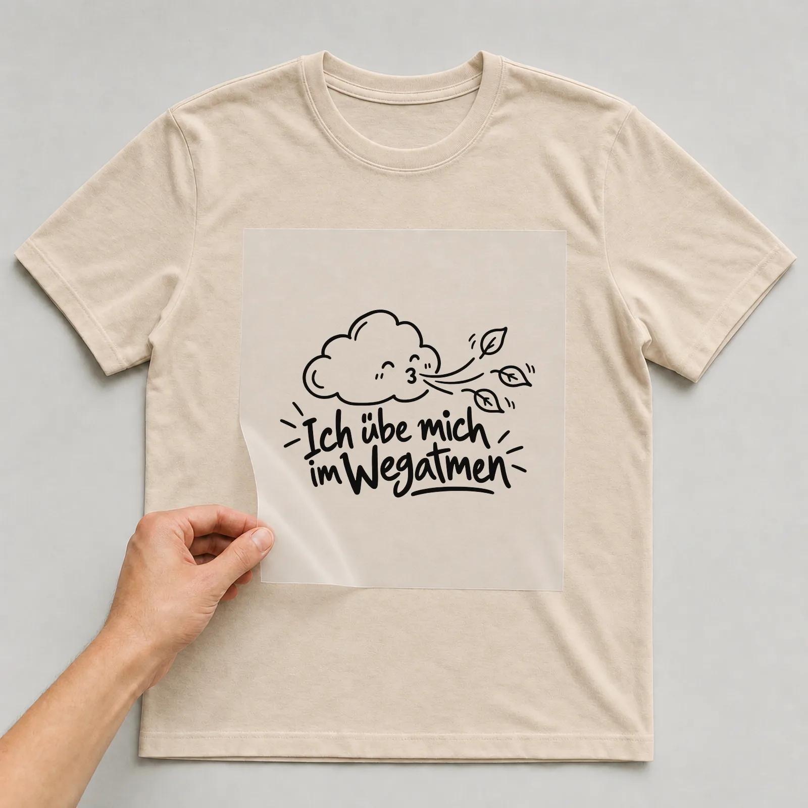 Bügelbild „Ich übe mich im Wegatmen“ auf beigem T-Shirt, Folie wird aufgelegt