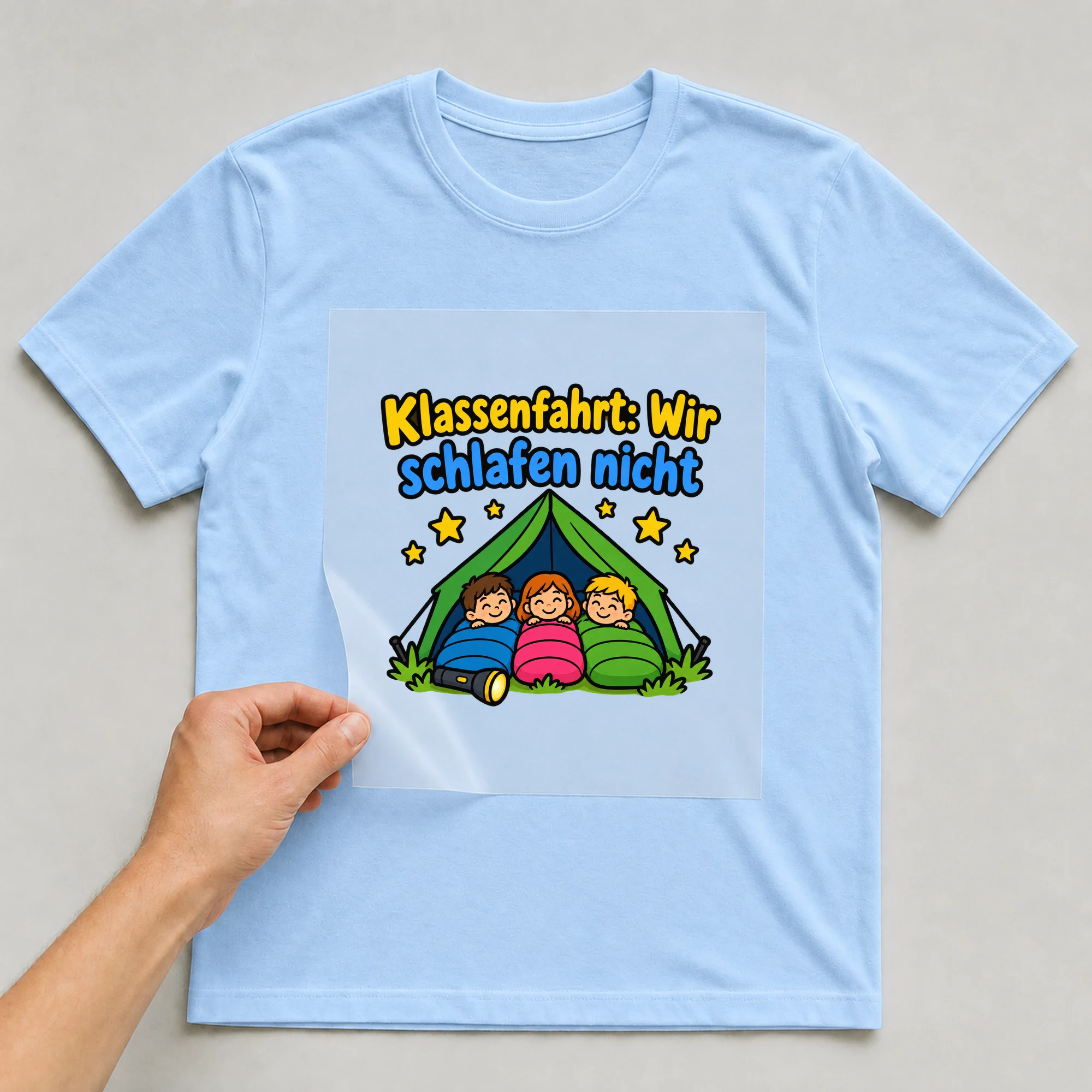 Bügelbild „Klassenfahrt: Wir schlafen nicht“ auf babyblauem T-Shirt, Folie wird aufgelegt