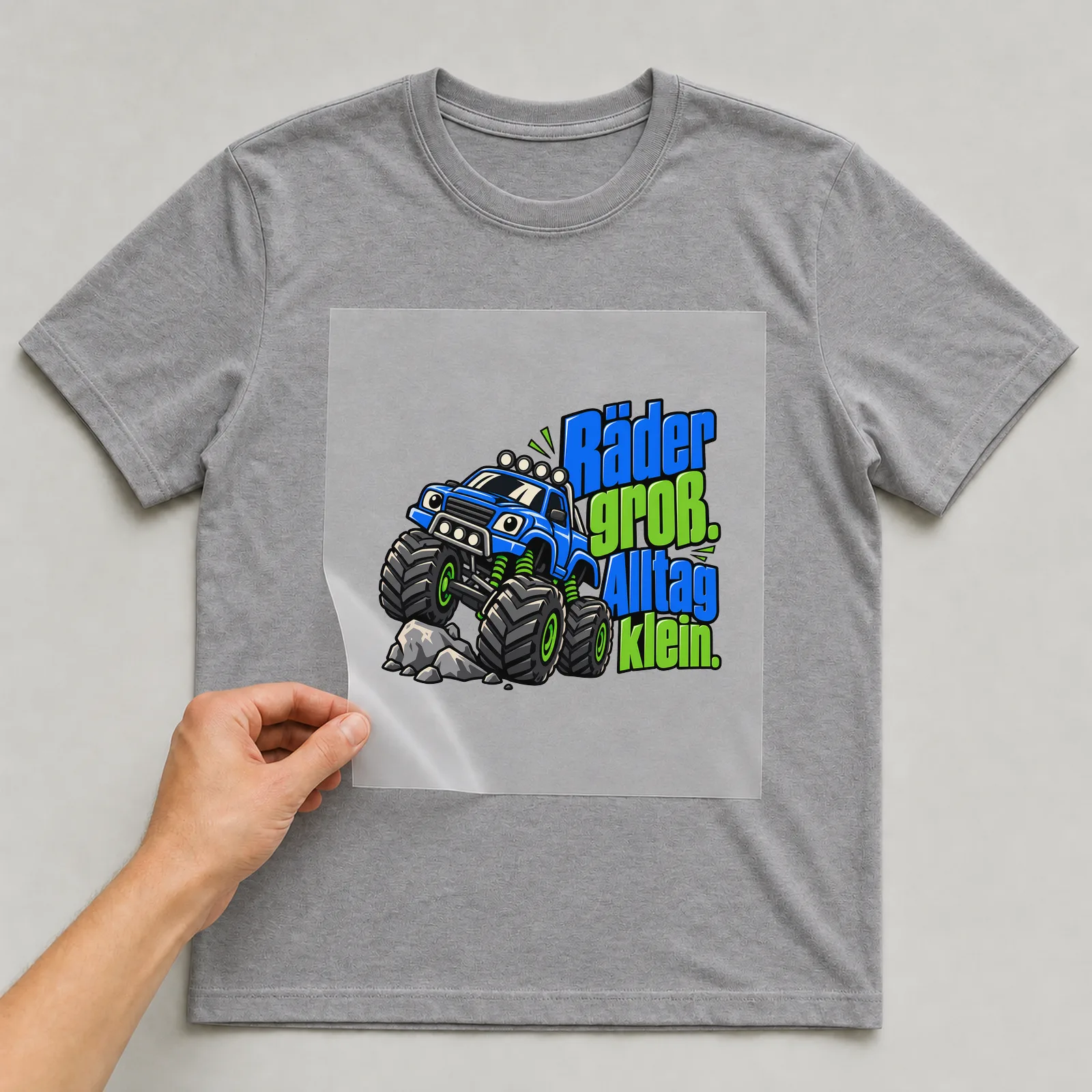 Bügelbild „Räder groß. Alltag klein.“ auf grauem T-Shirt, Folie wird aufgelegt
