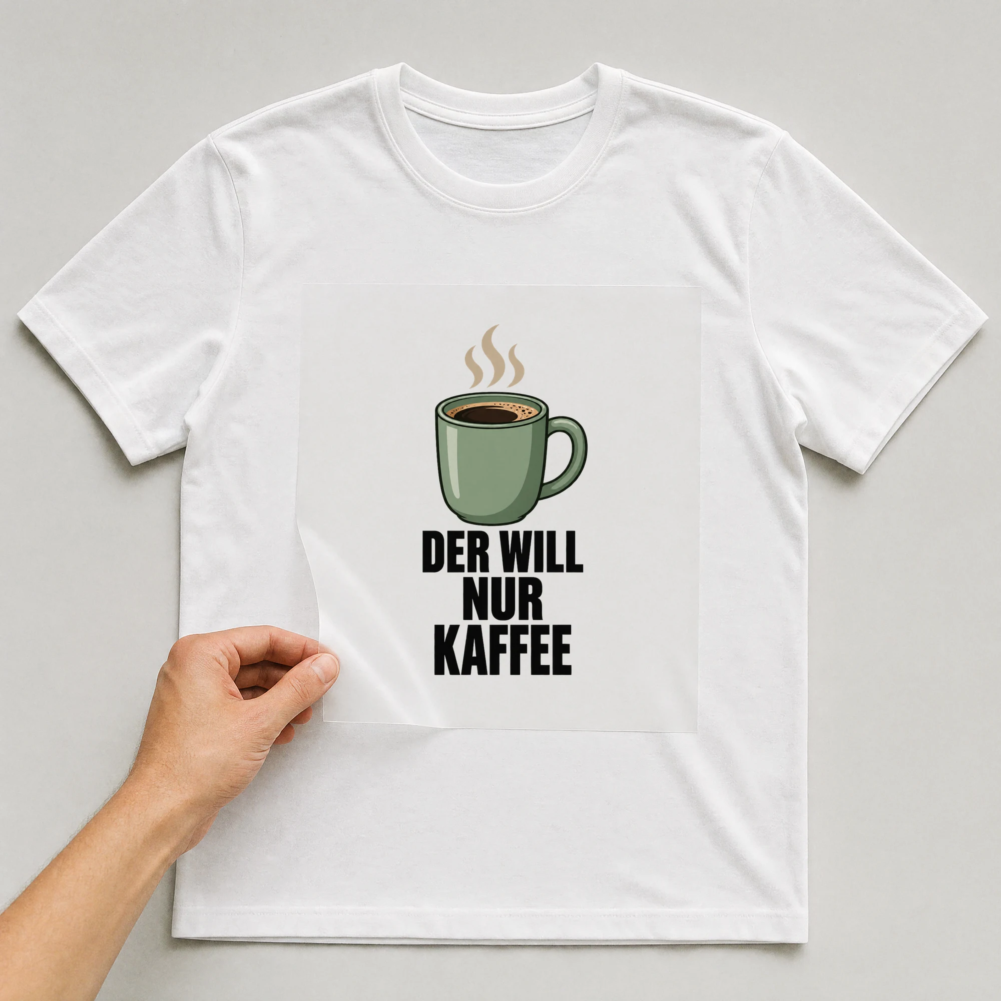 Bügelbild „Der will nur Kaffee“ auf weißem T-Shirt, Folie wird aufgelegt