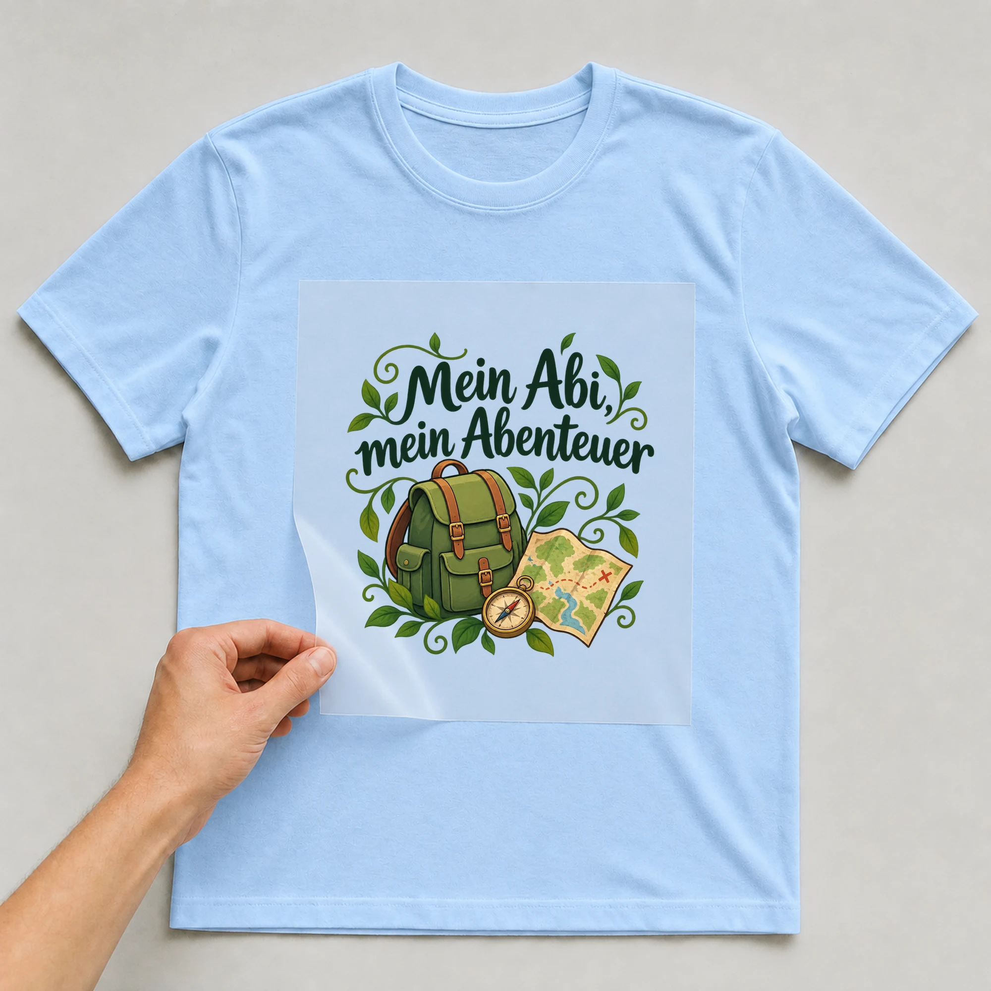 Bügelbild „Mein Abi, mein Abenteuer“ auf babyblauem T-Shirt, Folie wird aufgelegt