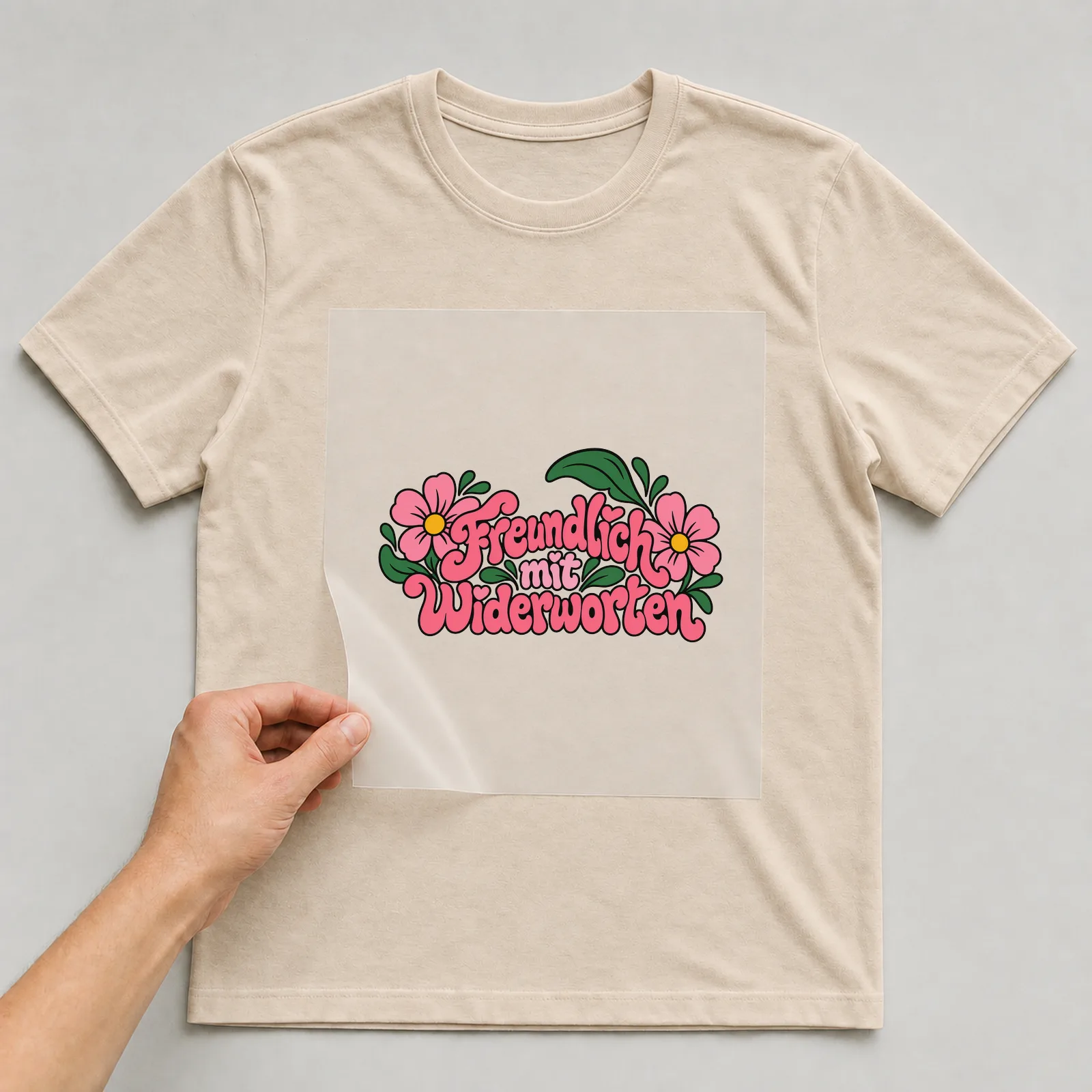 Bügelbild „Freundlich mit Widerworten“ auf beigem T-Shirt, Folie wird aufgelegt