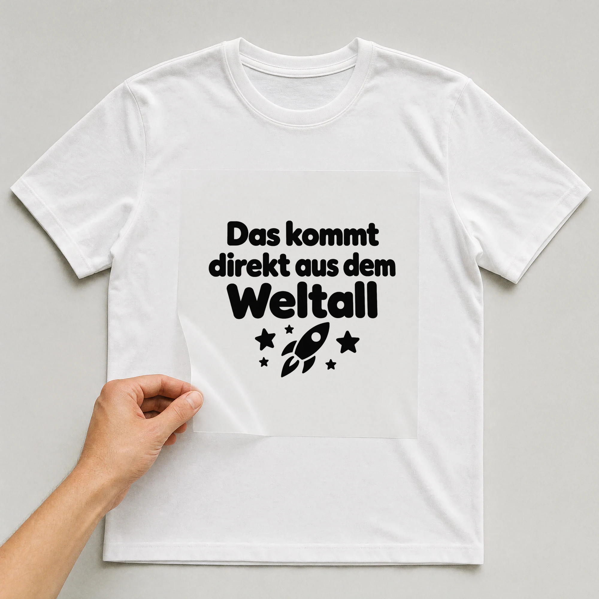 Bügelbild „Das kommt direkt aus dem Weltall“ auf weißem T-Shirt, Folie wird aufgelegt