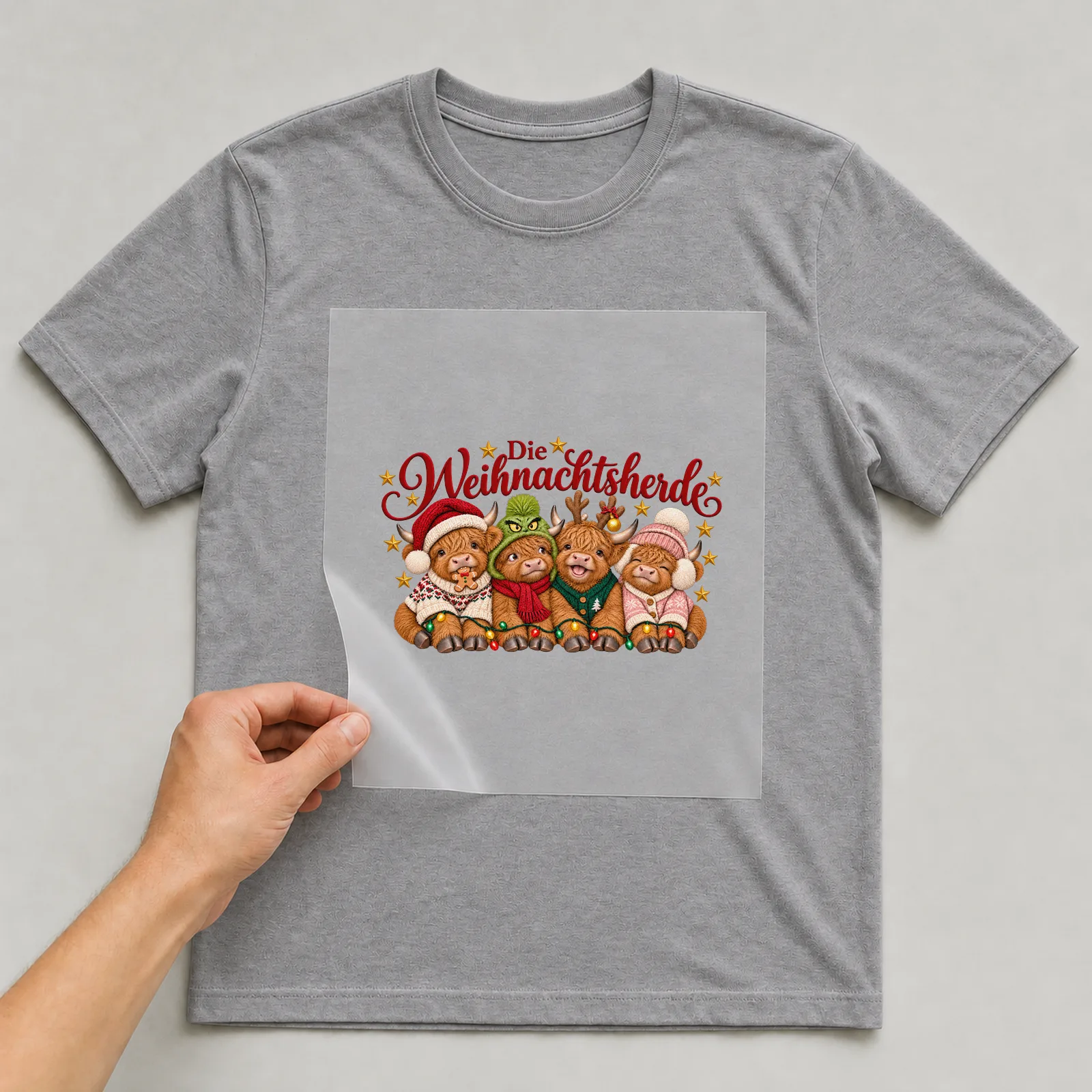 Bügelbild Die Weihnachtsherde auf grauem T-Shirt, Folie wird aufgelegt