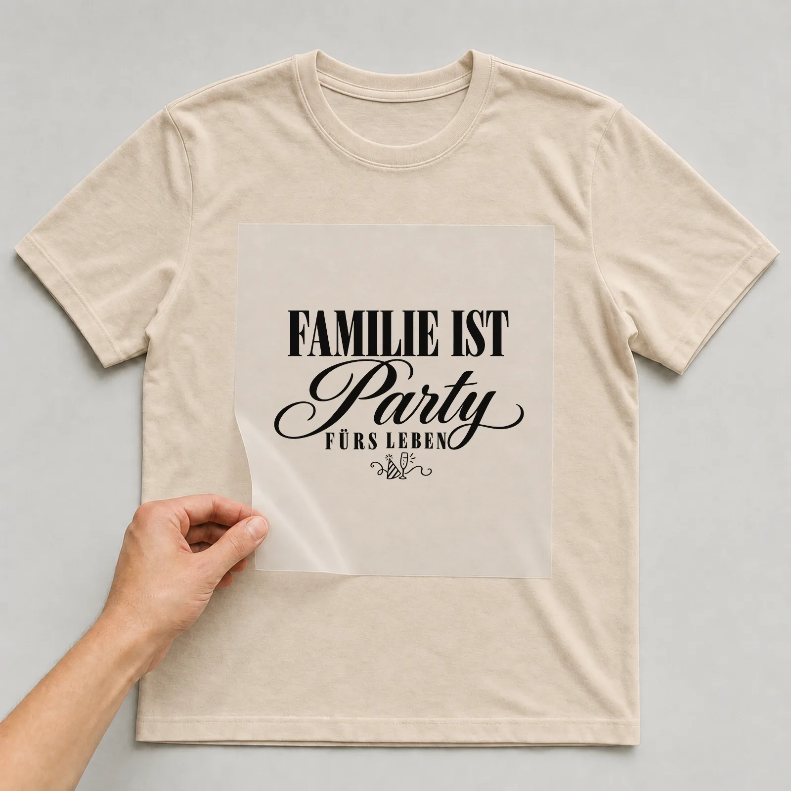 Bügelbild „Familie ist Party fürs Leben“ auf beigem T-Shirt, Folie wird aufgelegt