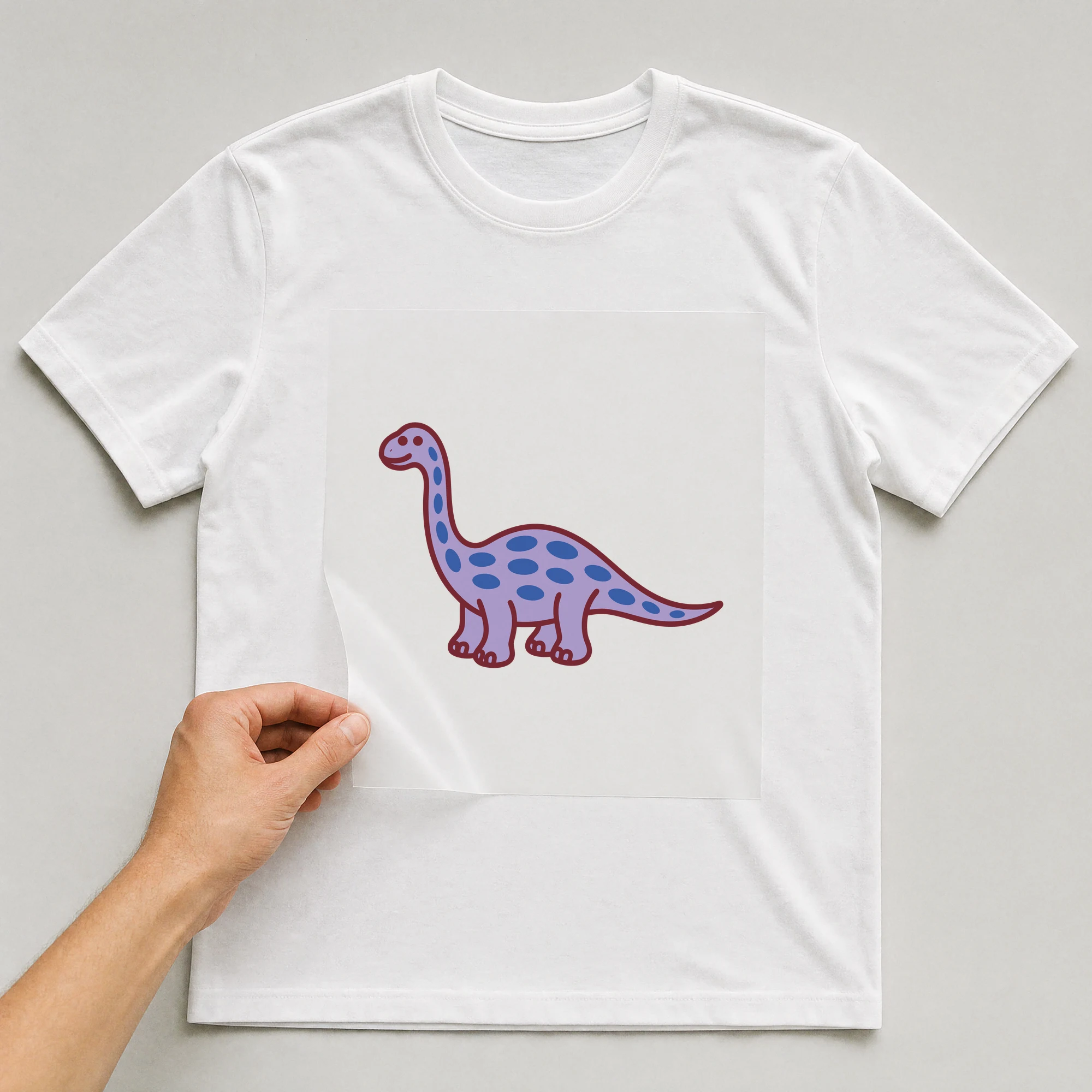Bügelbild „Dino Langhals“ auf weißem T-Shirt, Folie wird aufgelegt