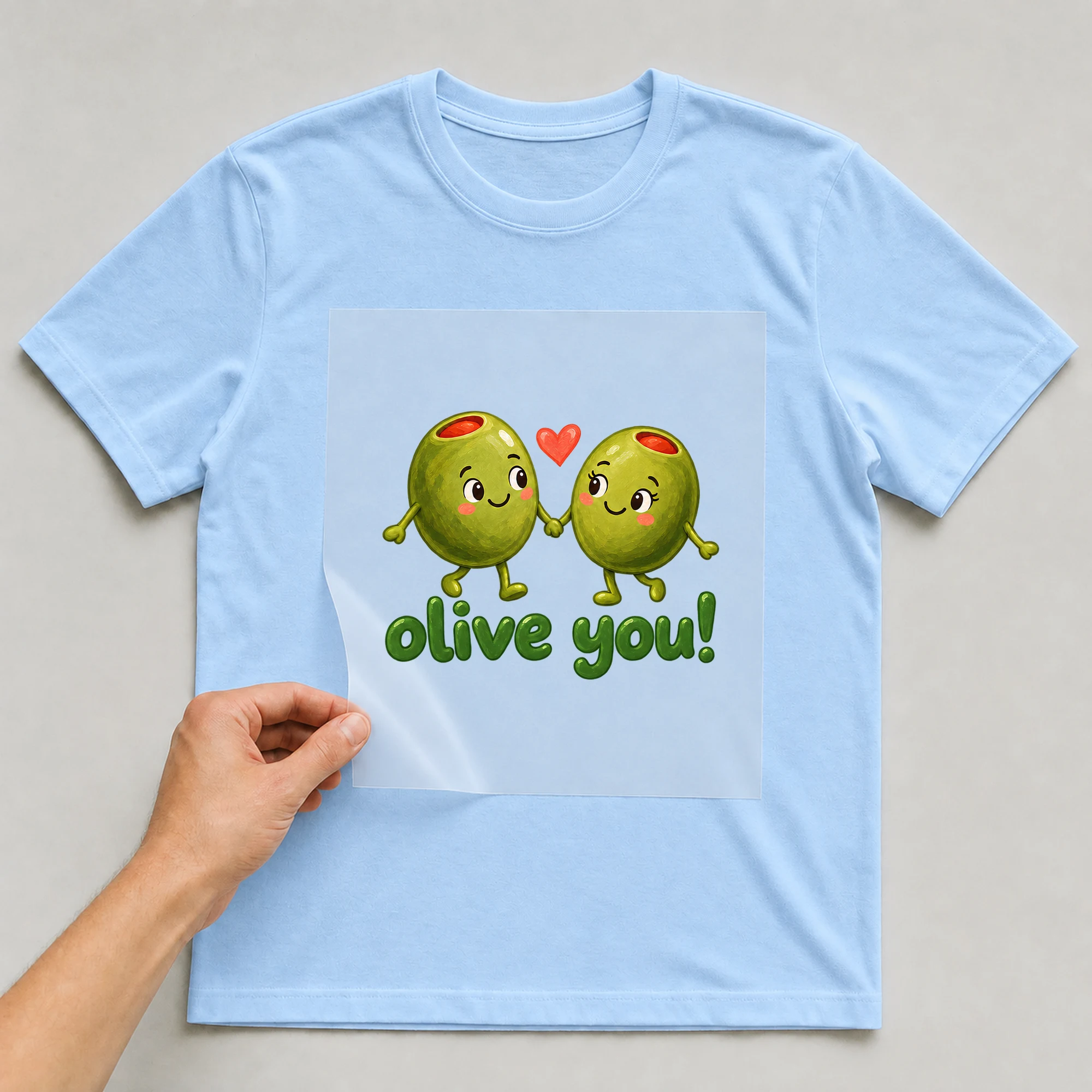 Bügelbild „olive you!“ auf babyblauem T-Shirt, Folie wird aufgelegt