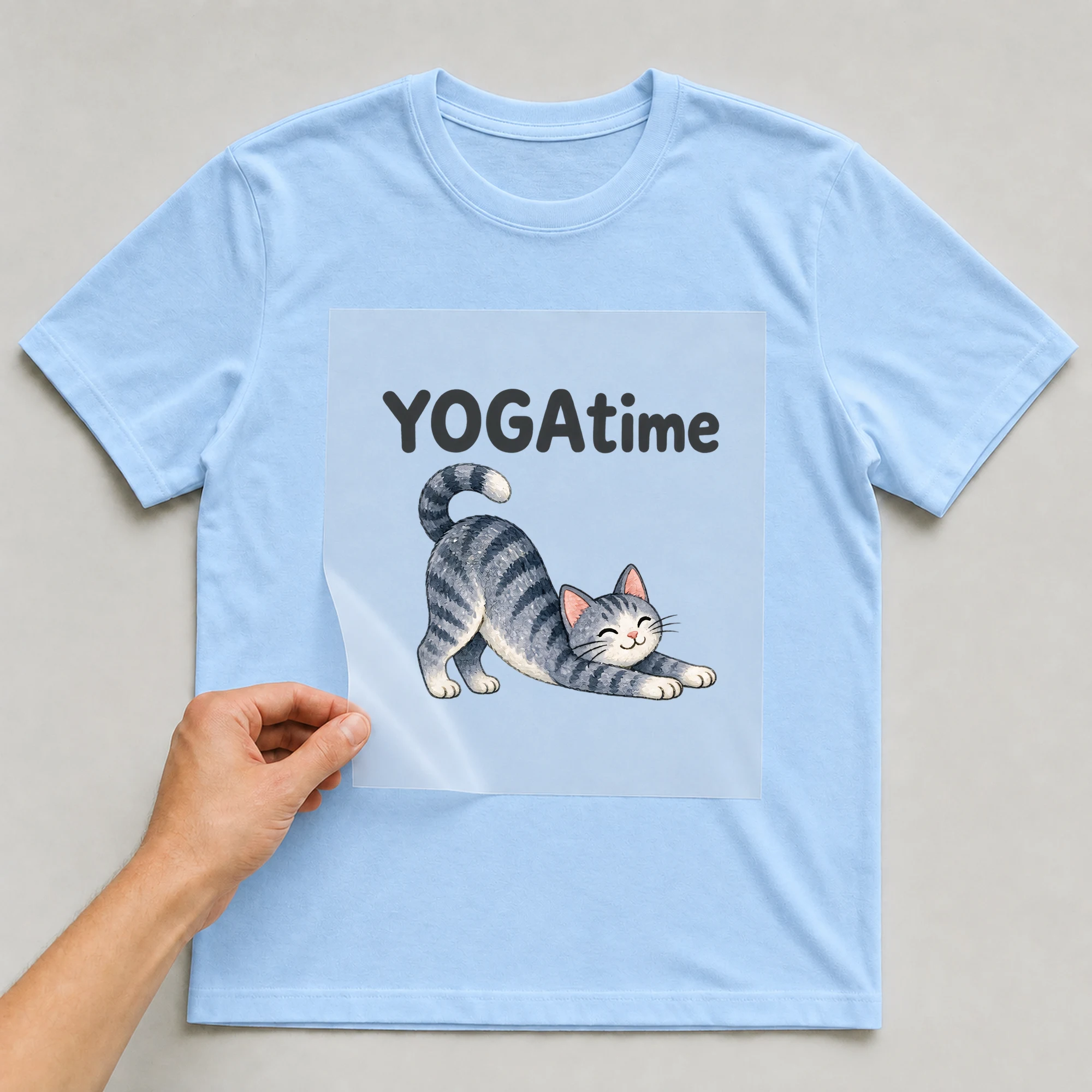 Bügelbild „YOGAtime“ auf babyblauem T-Shirt, Folie wird aufgelegt