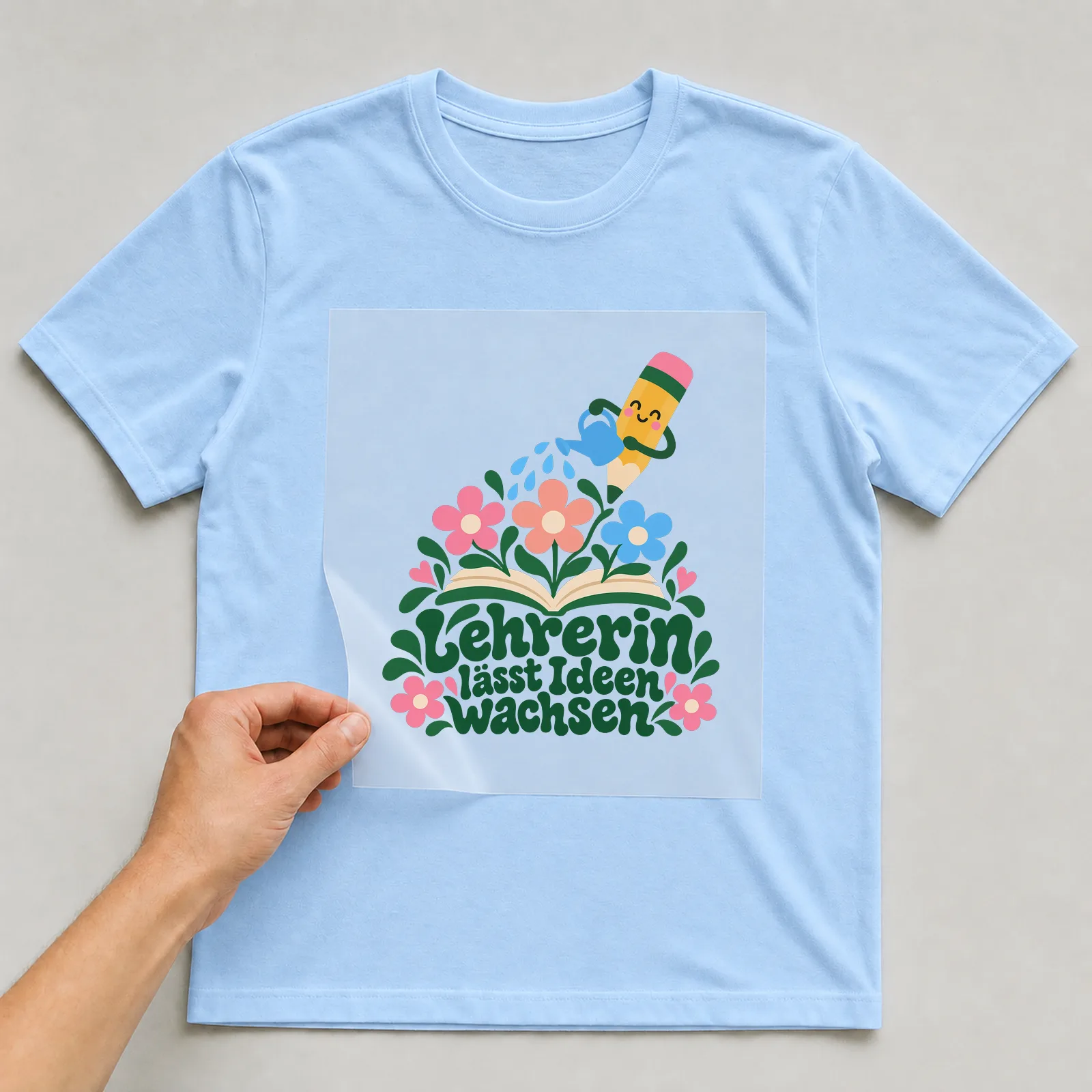 Bügelbild „Lehrerin lässt Ideen wachsen“ auf hellblauem T-Shirt, Folie wird aufgelegt