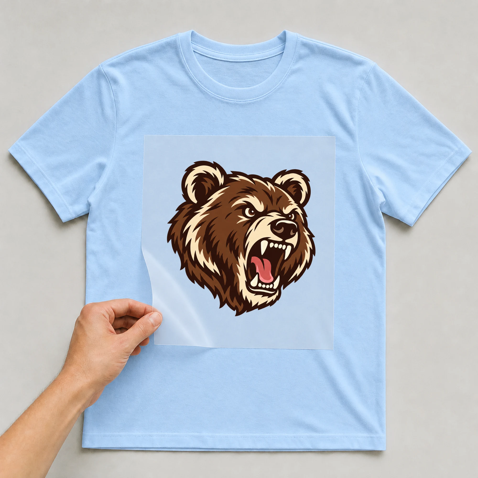 Bügelbild „BB021180-motiv-r03763“ auf babyblauem T-Shirt, Folie wird aufgelegt