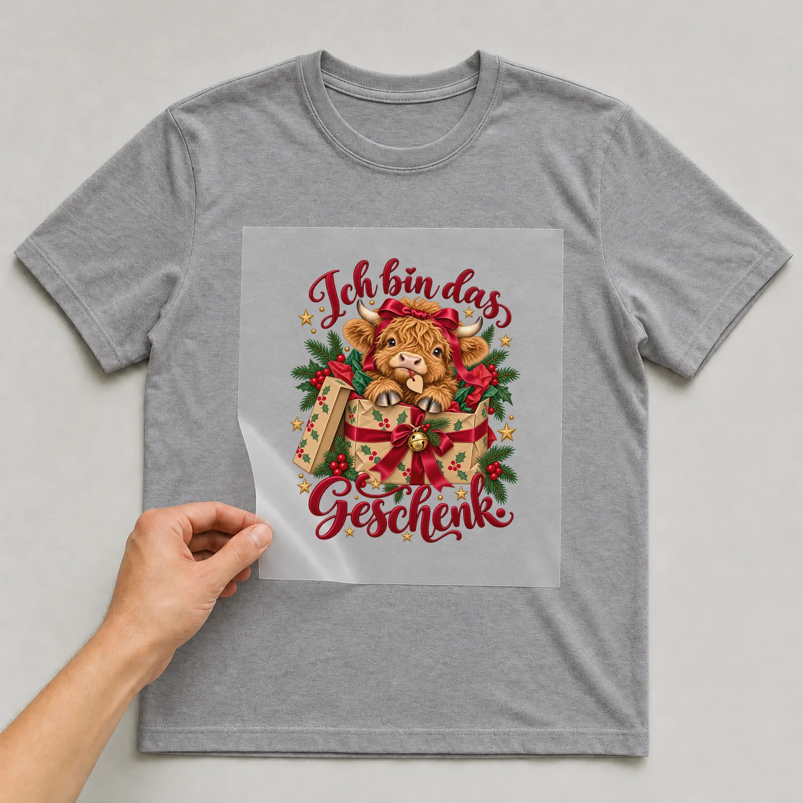 Bügelbild Ich bin das Geschenk. auf grauem T-Shirt, Folie wird aufgelegt