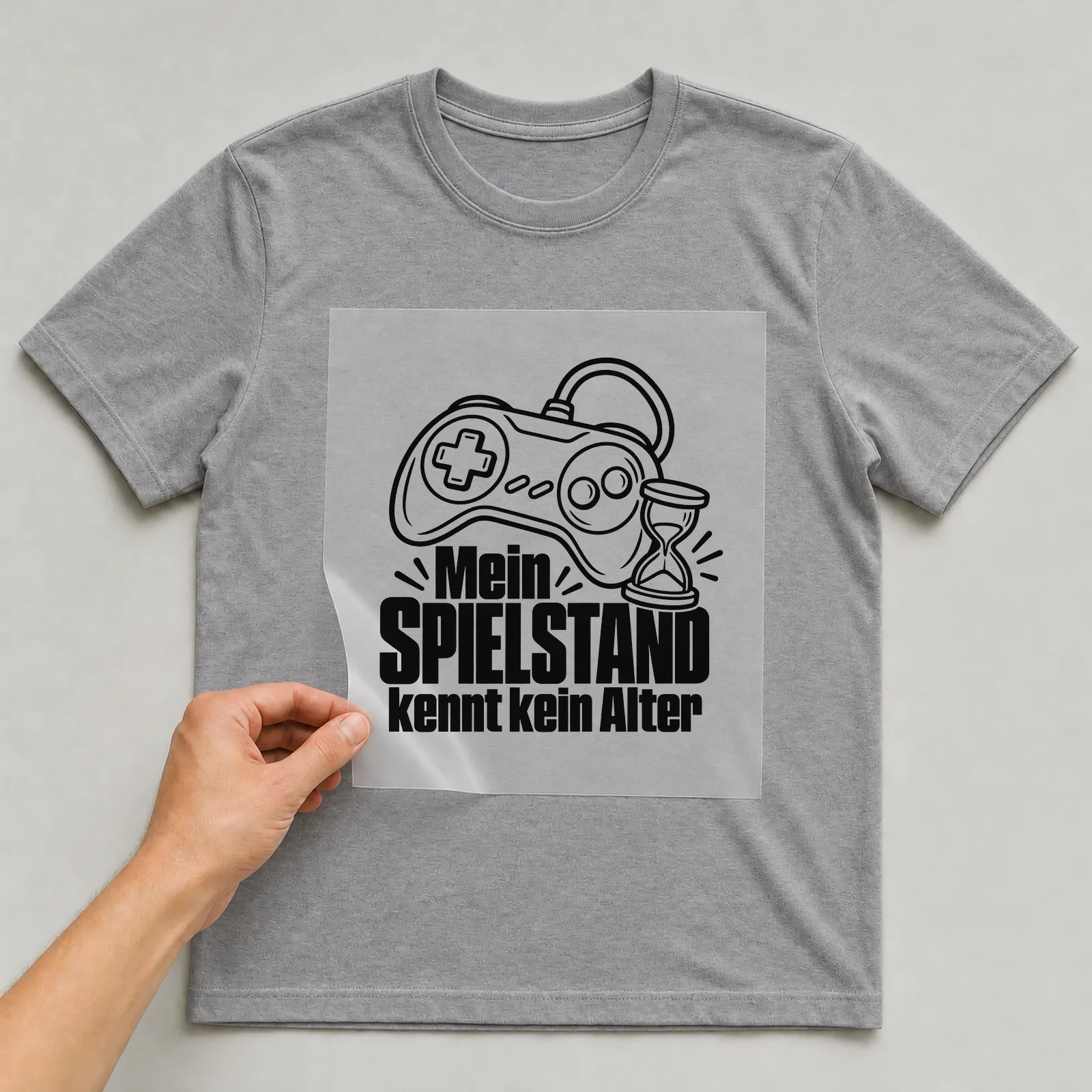 Bügelbild „Mein Spielstand kennt kein Alter“ auf grauem T-Shirt, Folie wird aufgelegt