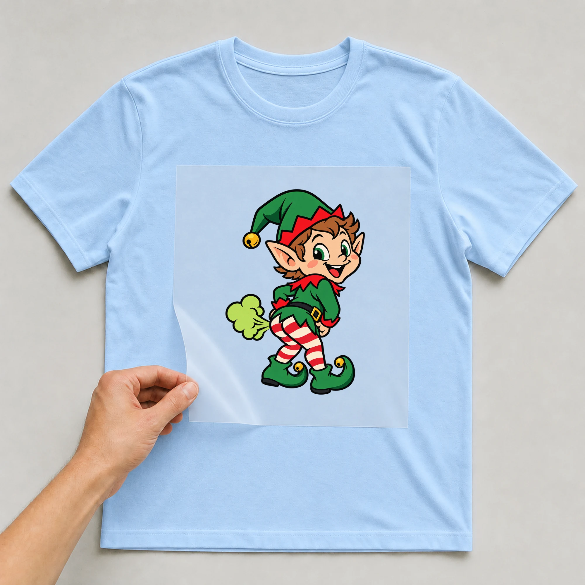 Bügelbild „Pupsender Elf“ auf babyblauem T-Shirt, Folie wird aufgelegt