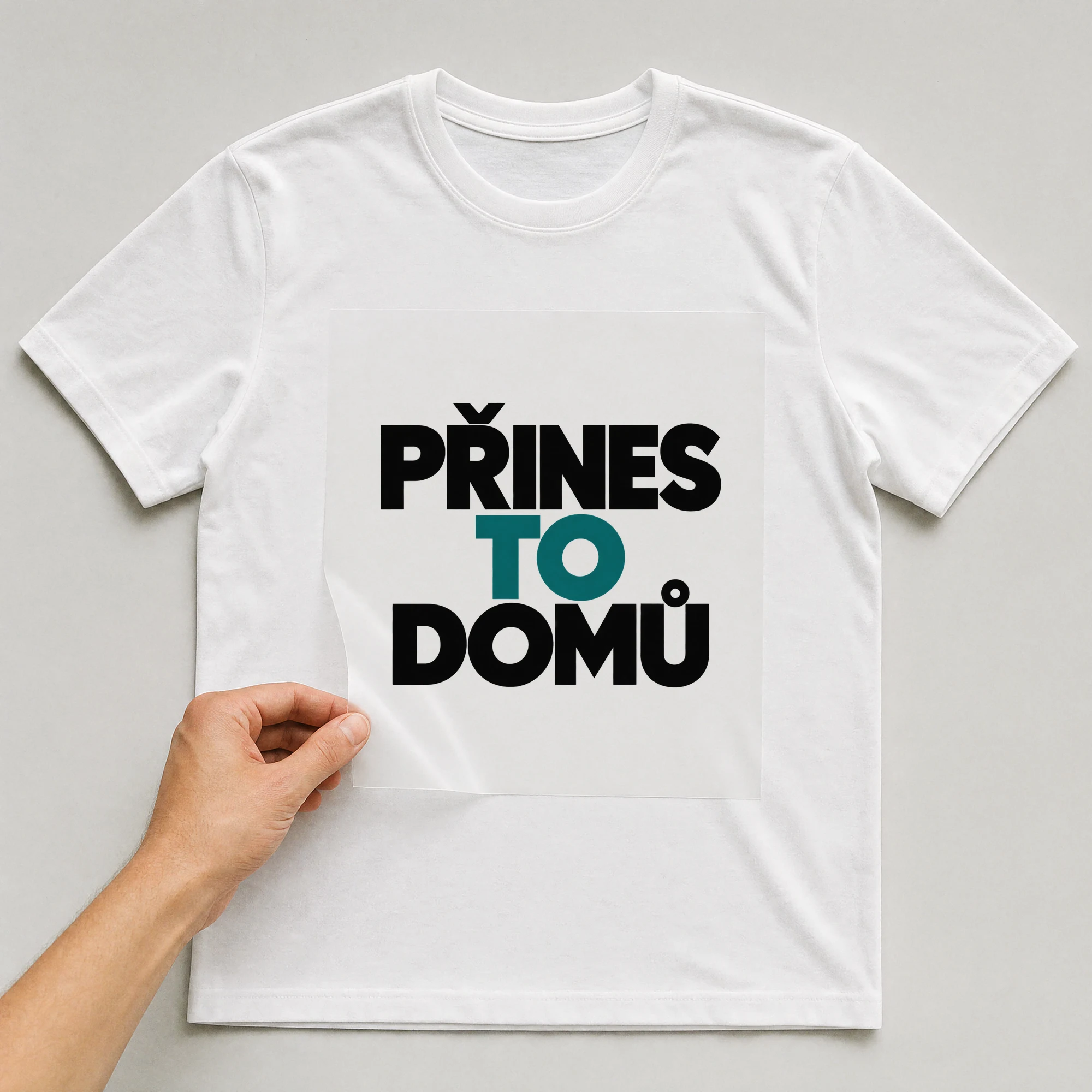 Bügelbild „Přines To Domů“ auf weißem T-Shirt, Folie wird aufgelegt