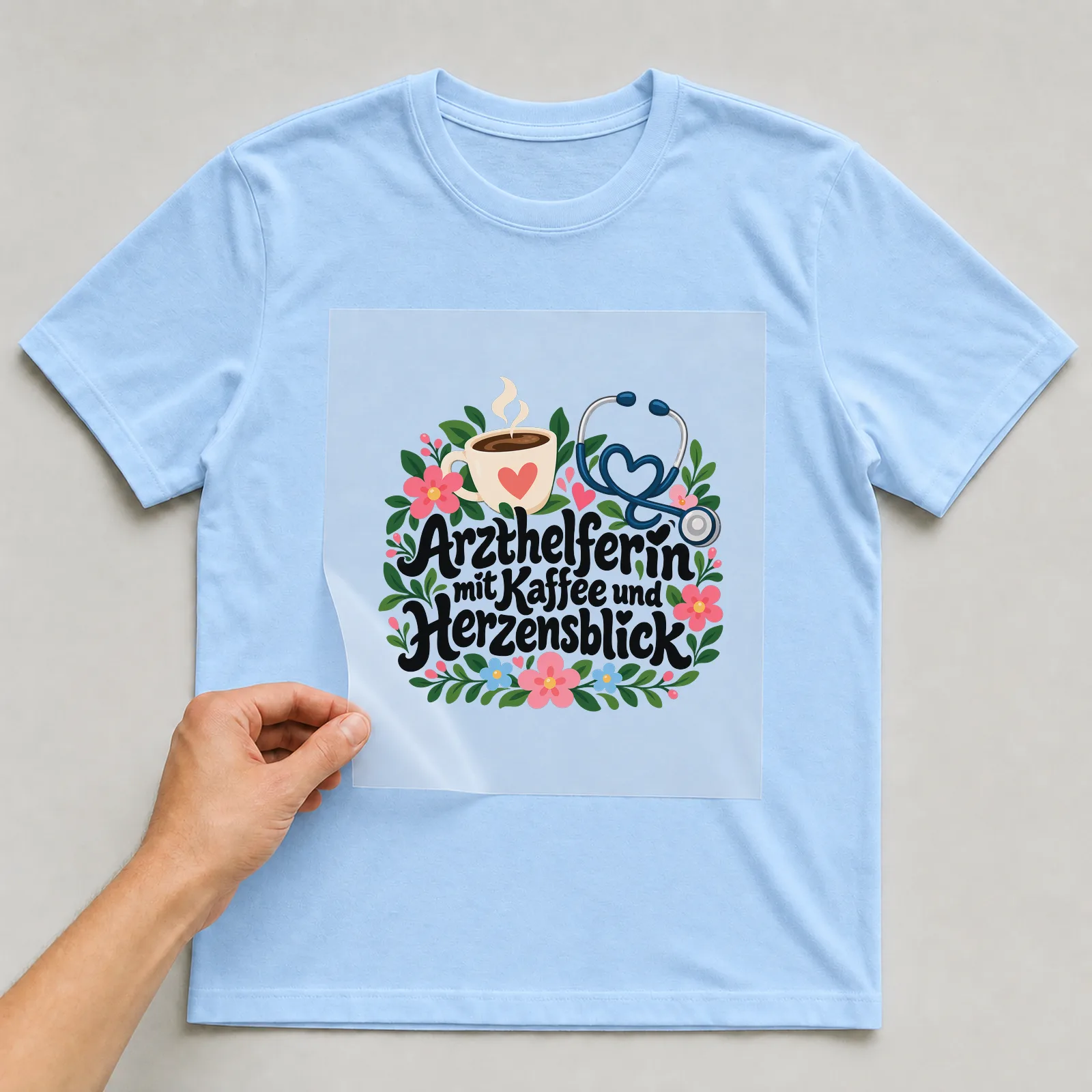 Bügelbild „Arzthelferin mit Kaffee und Herzensblick“ auf hellblauem T-Shirt, Folie wird aufgelegt
