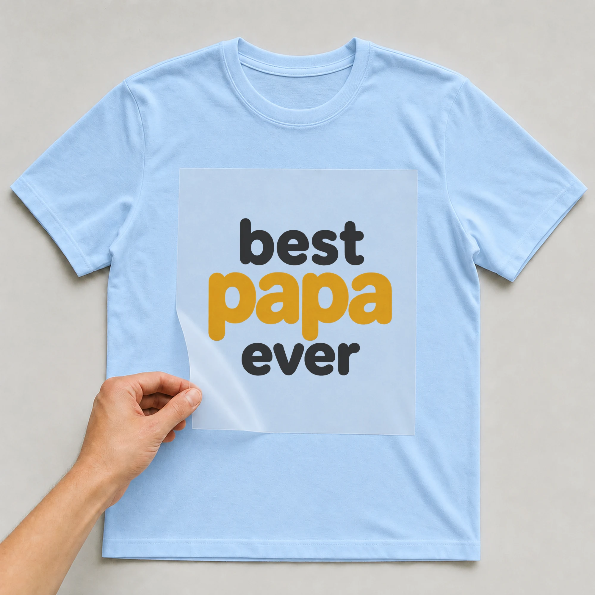 Bügelbild „best papa ever“ auf babyblauem T-Shirt, Folie wird aufgelegt
