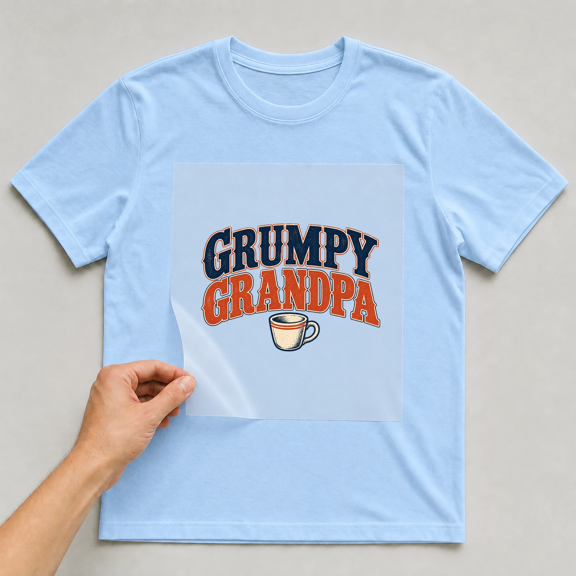 Bügelbild „Grumpy Grandpa“ auf babyblauem T-Shirt, Folie wird aufgelegt