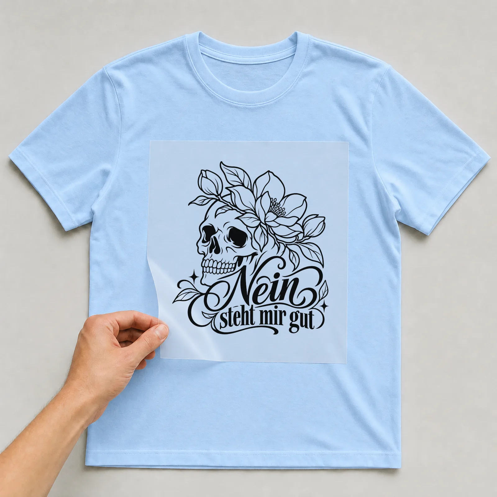 Bügelbild „Nein steht mir gut“ auf hellblauem T-Shirt, Folie wird aufgelegt