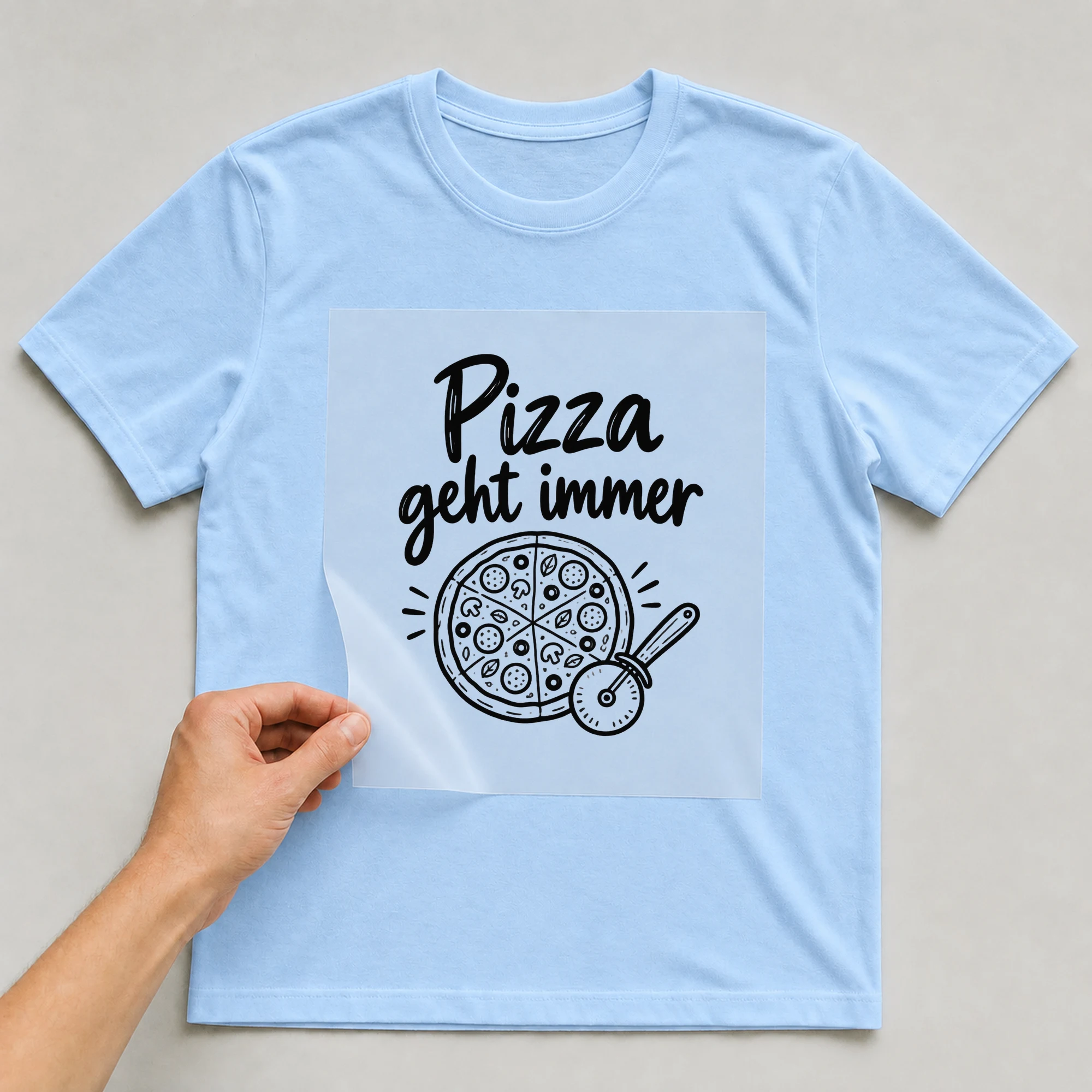 Bügelbild „Pizza geht immer“ auf babyblauem T-Shirt, Folie wird aufgelegt
