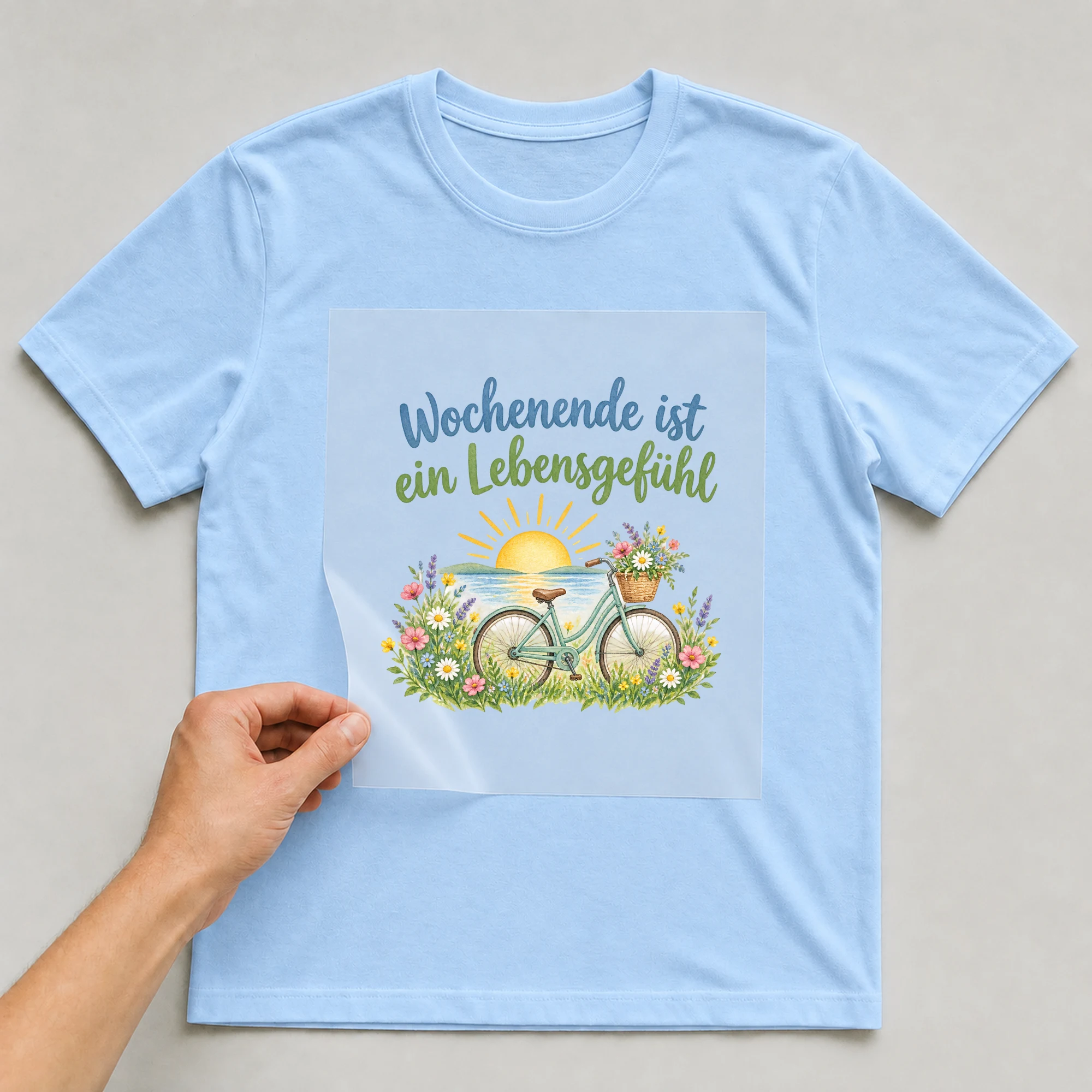 Bügelbild „Wochenende ist ein Lebensgefühl“ auf babyblauem T-Shirt, Folie wird aufgelegt