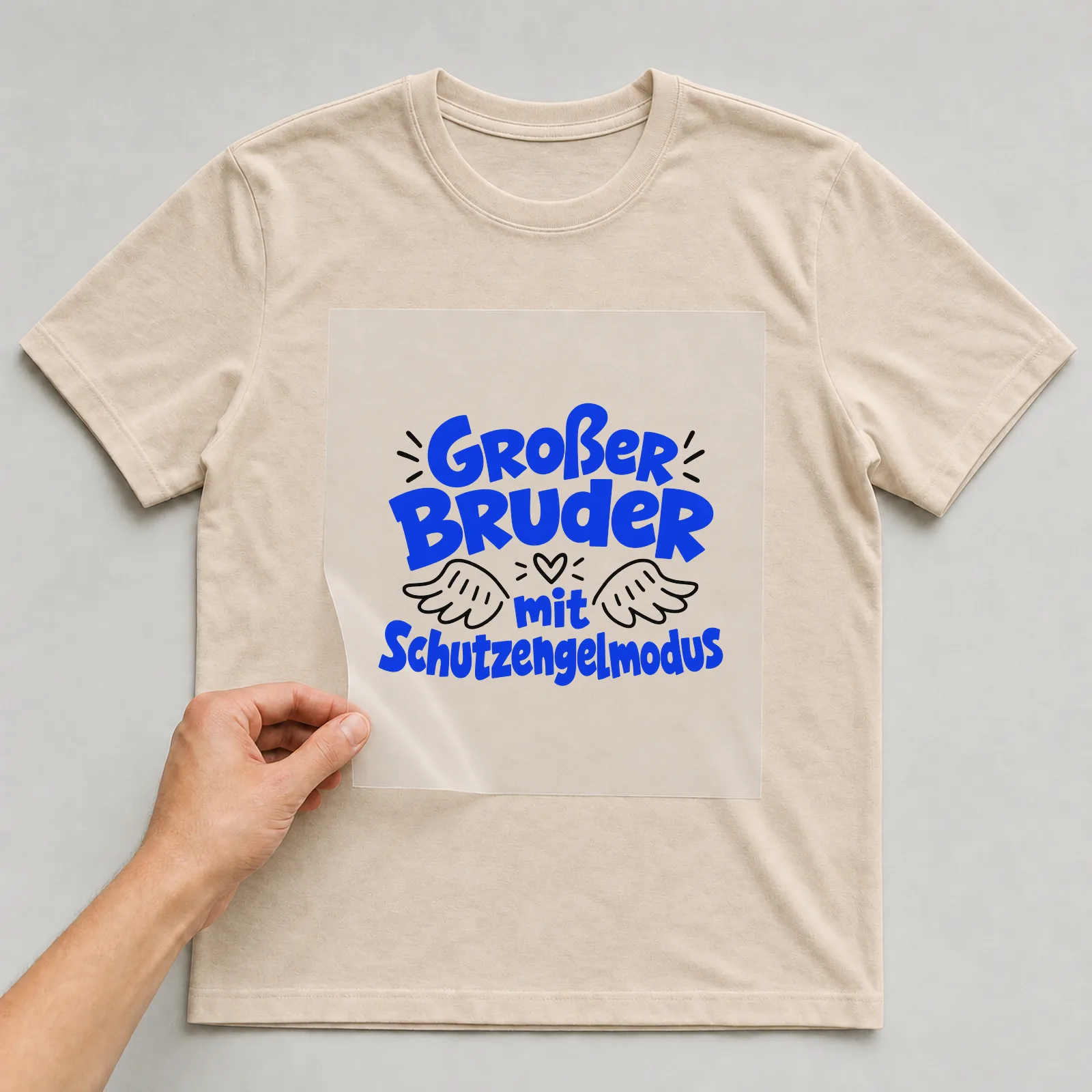 Bügelbild „Großer Bruder mit Schutzengelmodus“ auf beigem T-Shirt, Folie wird aufgelegt
