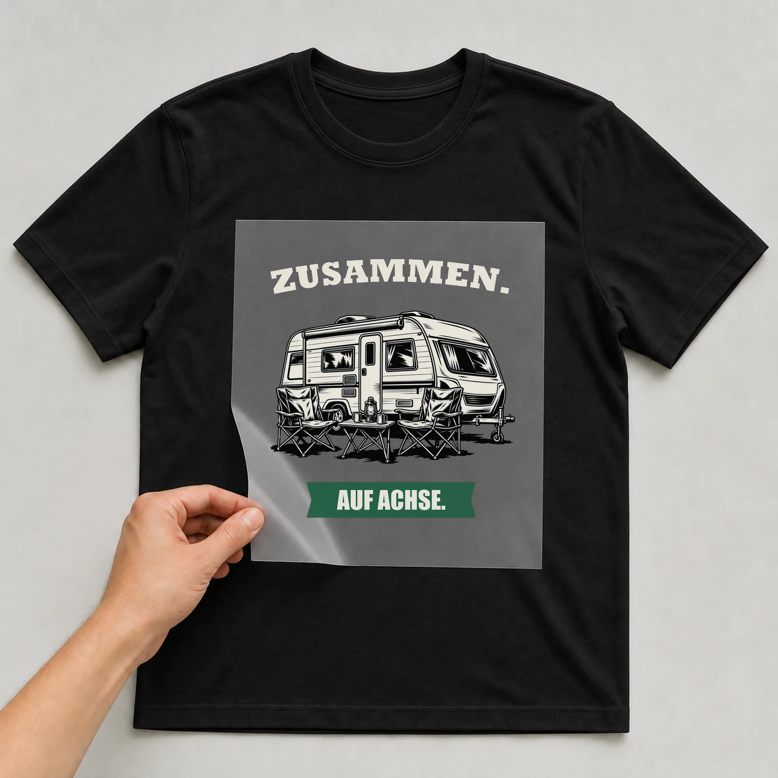 Bügelbild „Zusammen. Auf Achse.“ auf schwarzem T-Shirt, Folie wird aufgelegt