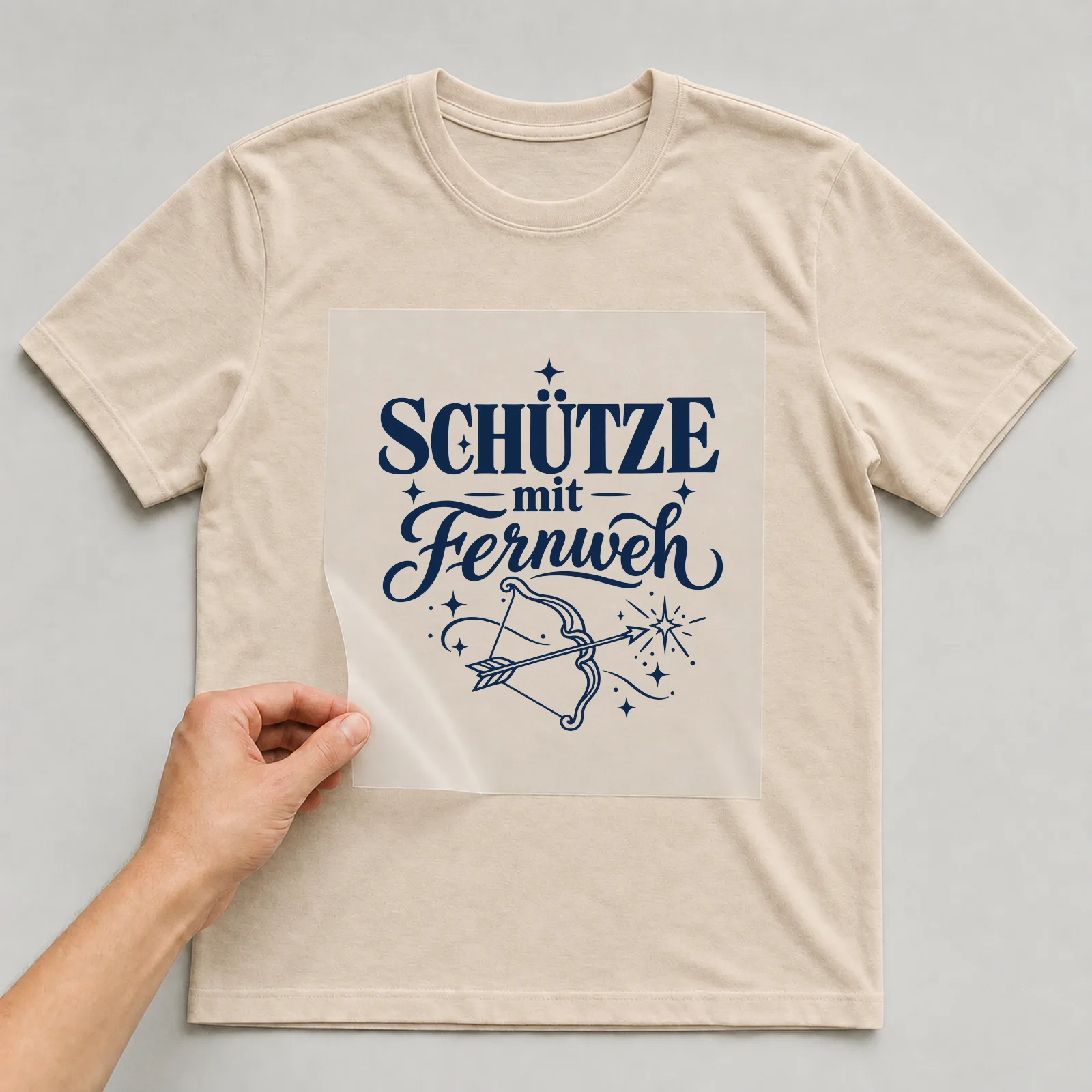 Bügelbild „Schütze mit Fernweh“ auf beigem T-Shirt, Folie wird aufgelegt