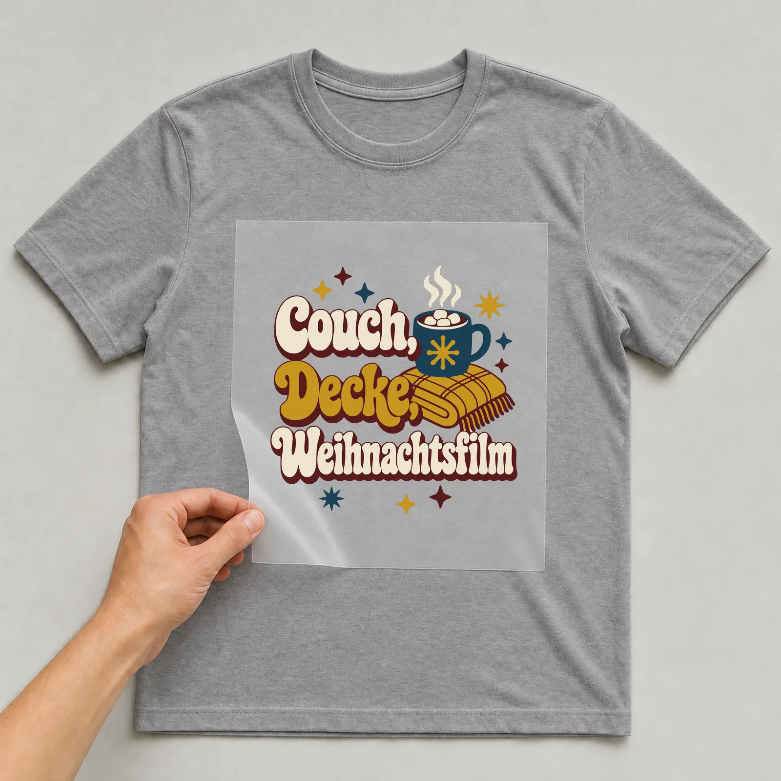 Bügelbild Couch, Decke, Weihnachtsfilm auf grauem T-Shirt, Folie wird aufgelegt