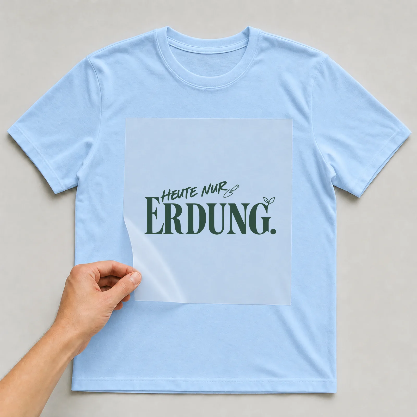 Bügelbild „Heute nur Erdung“ (Schrift Konturen, Nr. 2) auf hellblauem T-Shirt, Folie wird aufgelegt