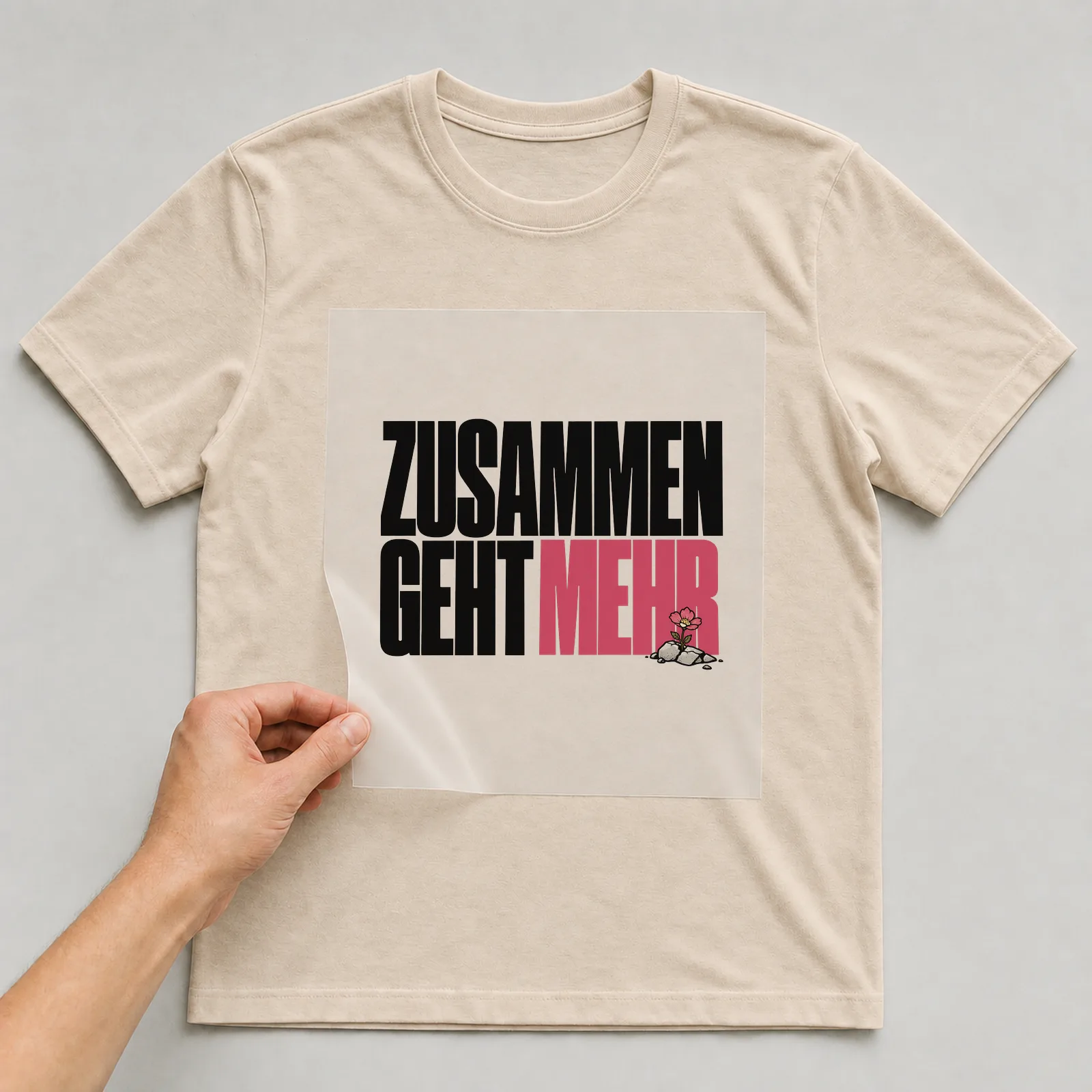 Bügelbild „Zusammen geht mehr“ auf beigem T-Shirt, Folie wird aufgelegt
