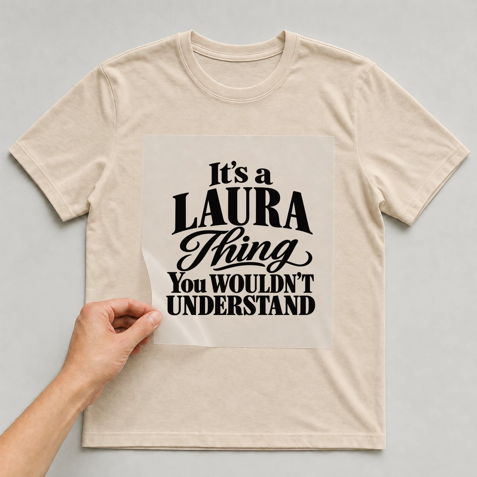Bügelbild „It's a LAURA Thing You WOULDN'T UNDERSTAND“ auf babyblauem T-Shirt, Folie wird aufgelegt