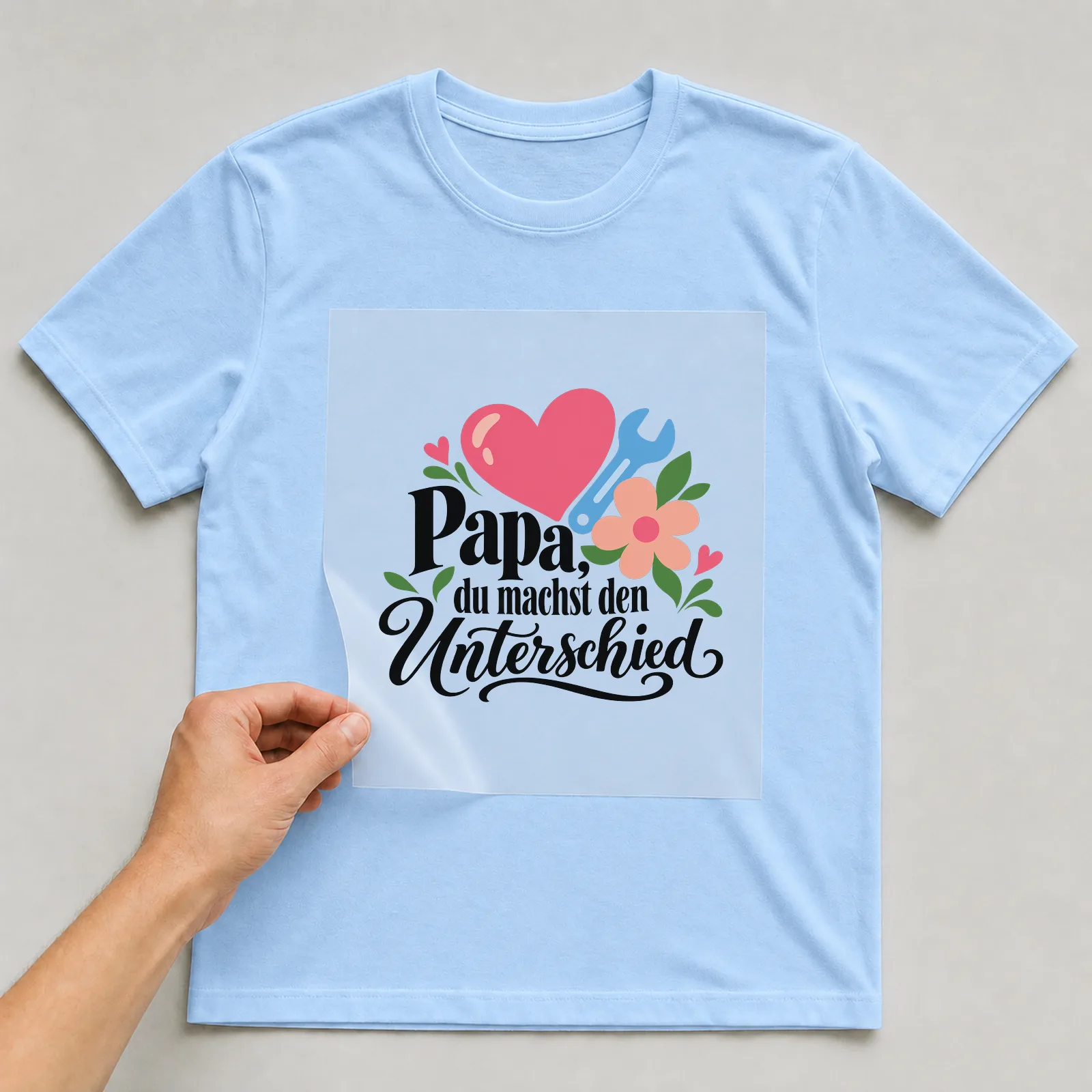 Bügelbild „Papa, du machst den Unterschied“ auf hellblauem T-Shirt, Folie wird aufgelegt