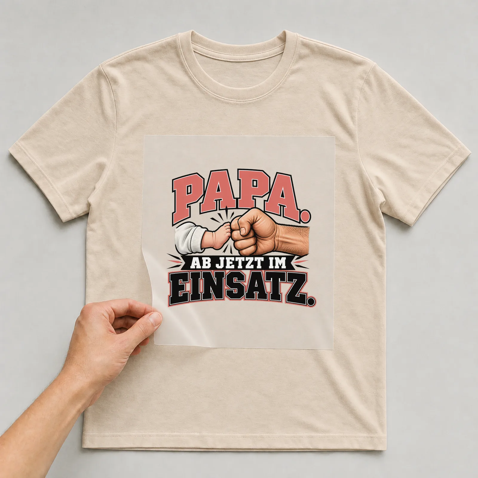 Bügelbild „Papa. Ab jetzt im Einsatz.“ auf beigem T-Shirt, Folie wird aufgelegt