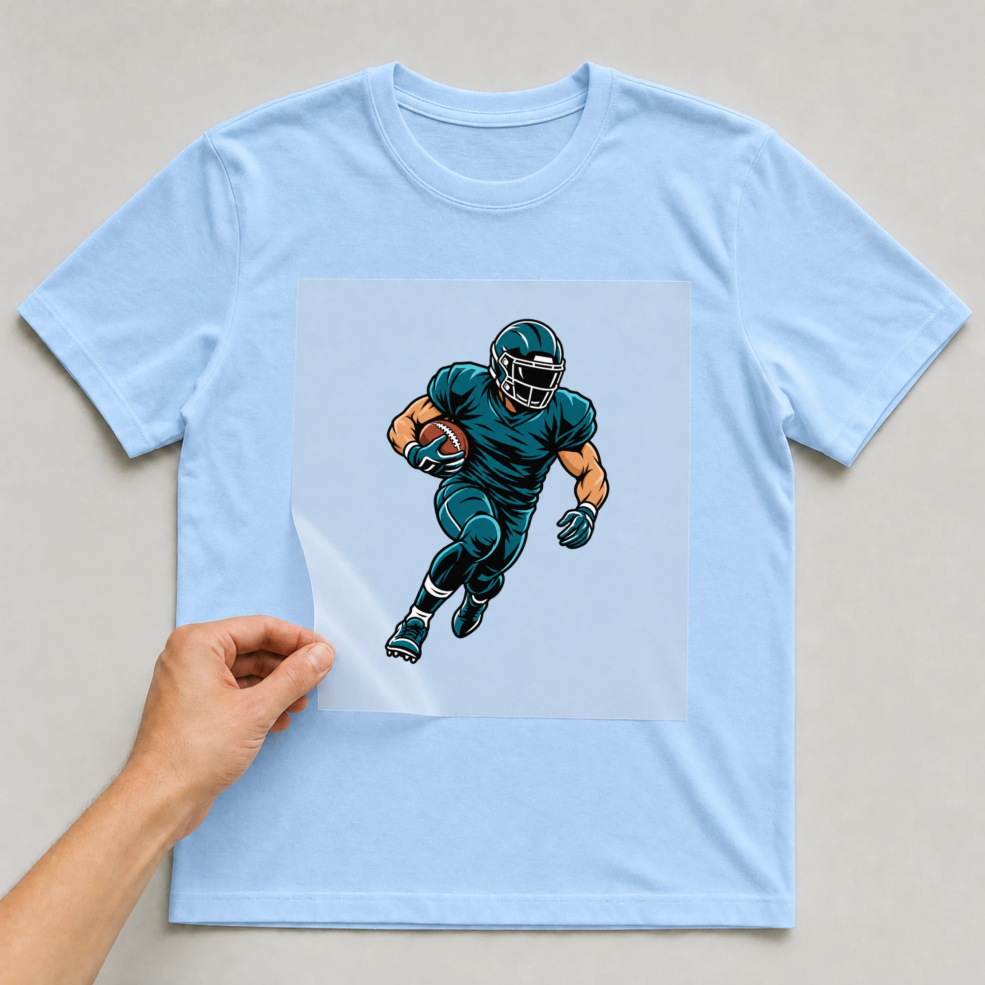Bügelbild „Football Player“ auf babyblauem T-Shirt, Folie wird aufgelegt
