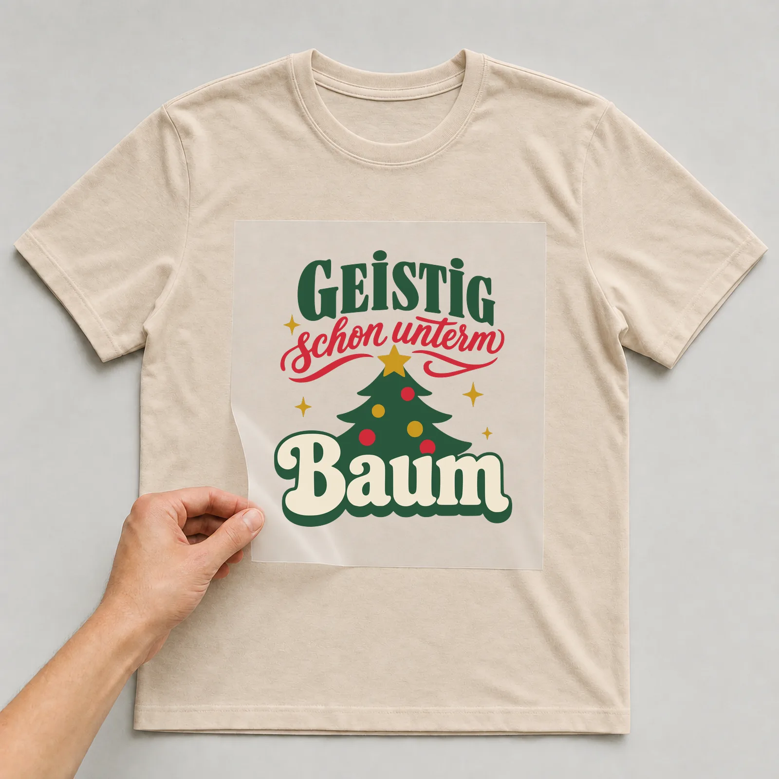 Bügelbild Geistig schon unterm Baum auf beigem T-Shirt, Folie wird aufgelegt