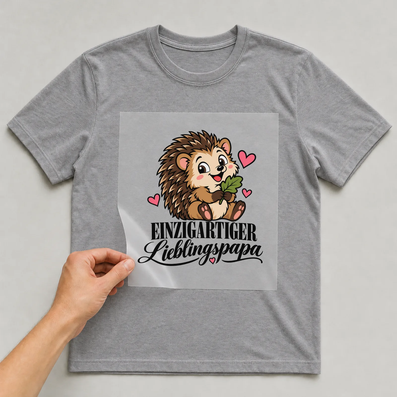Bügelbild „Einzigartiger Lieblingspapa“ auf grauem T-Shirt, Folie wird aufgelegt