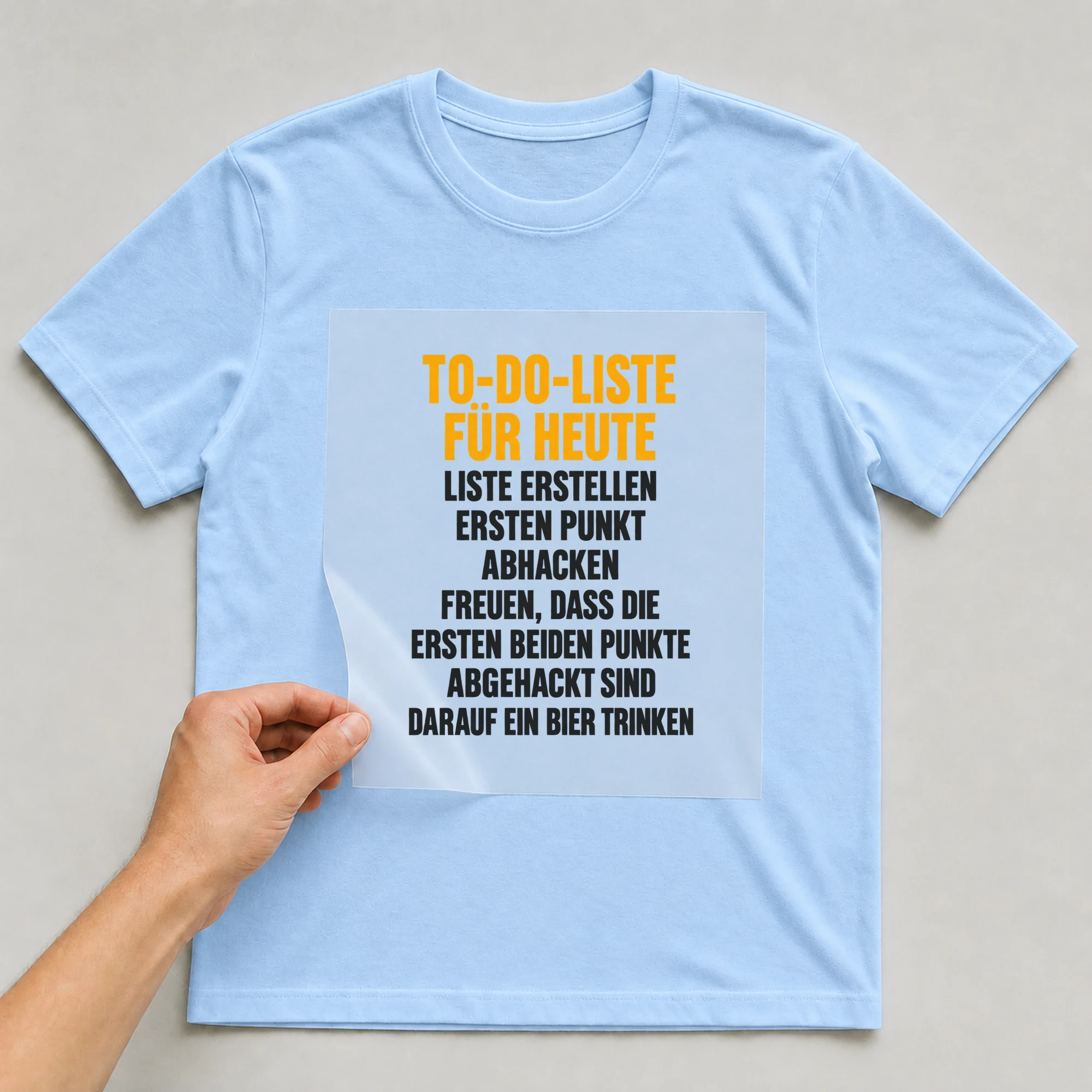 Bügelbild „To-do-liste für heute Liste erstellen ersten Punkt abhacken freuen, dass die“ auf babyblauem T-Shirt, Folie wird aufgelegt