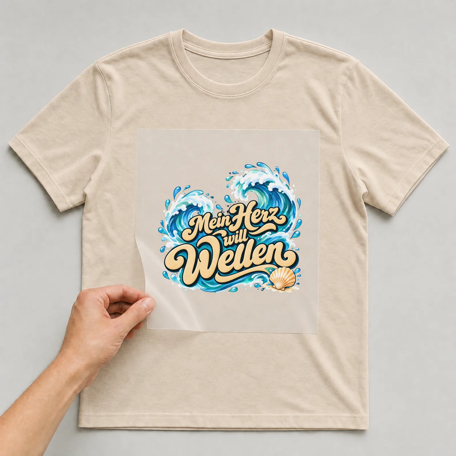 Bügelbild „Mein Herz will Wellen“ auf beigem T-Shirt, Folie wird aufgelegt