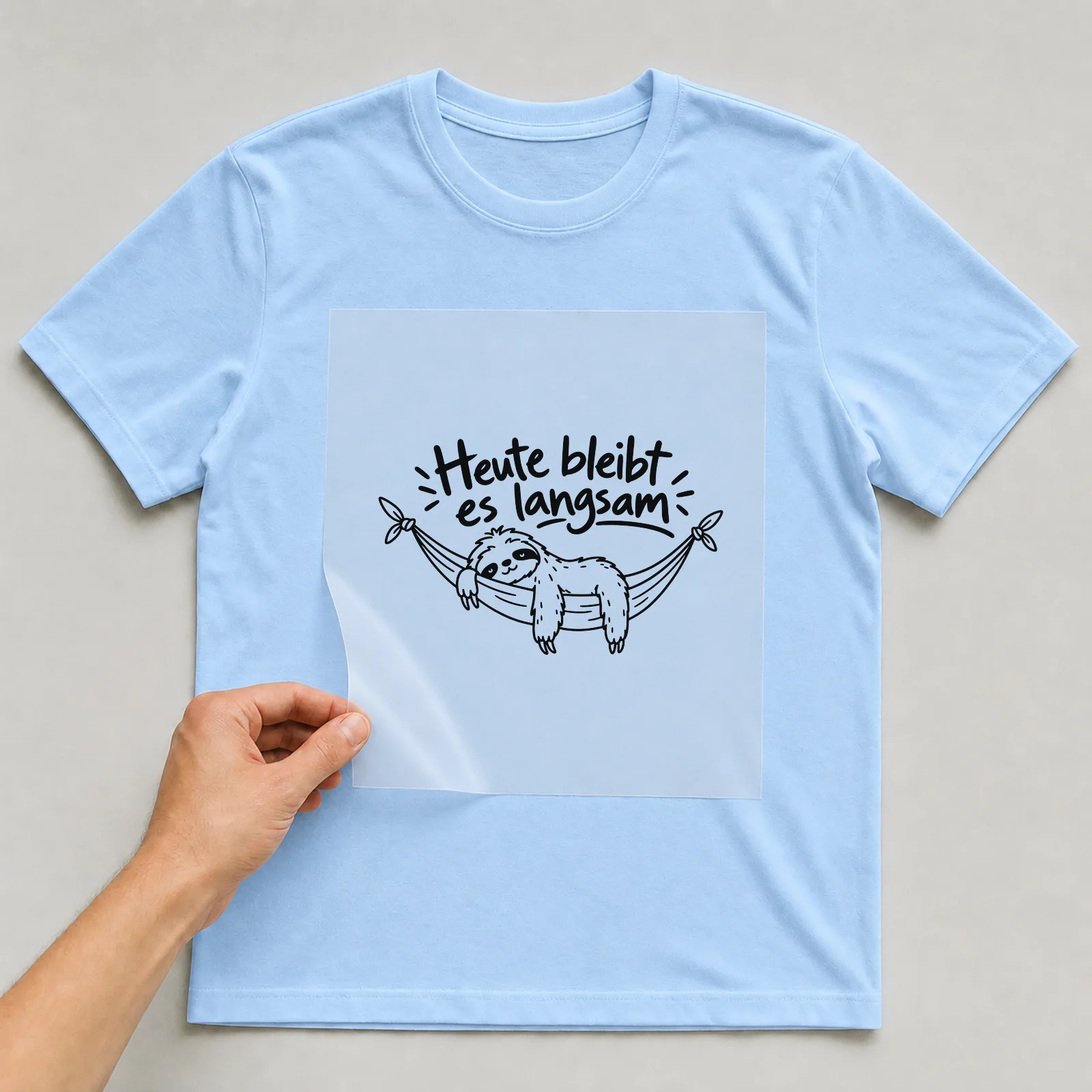 Bügelbild „Heute bleibt es langsam“ auf hellblauem T-Shirt, Folie wird aufgelegt